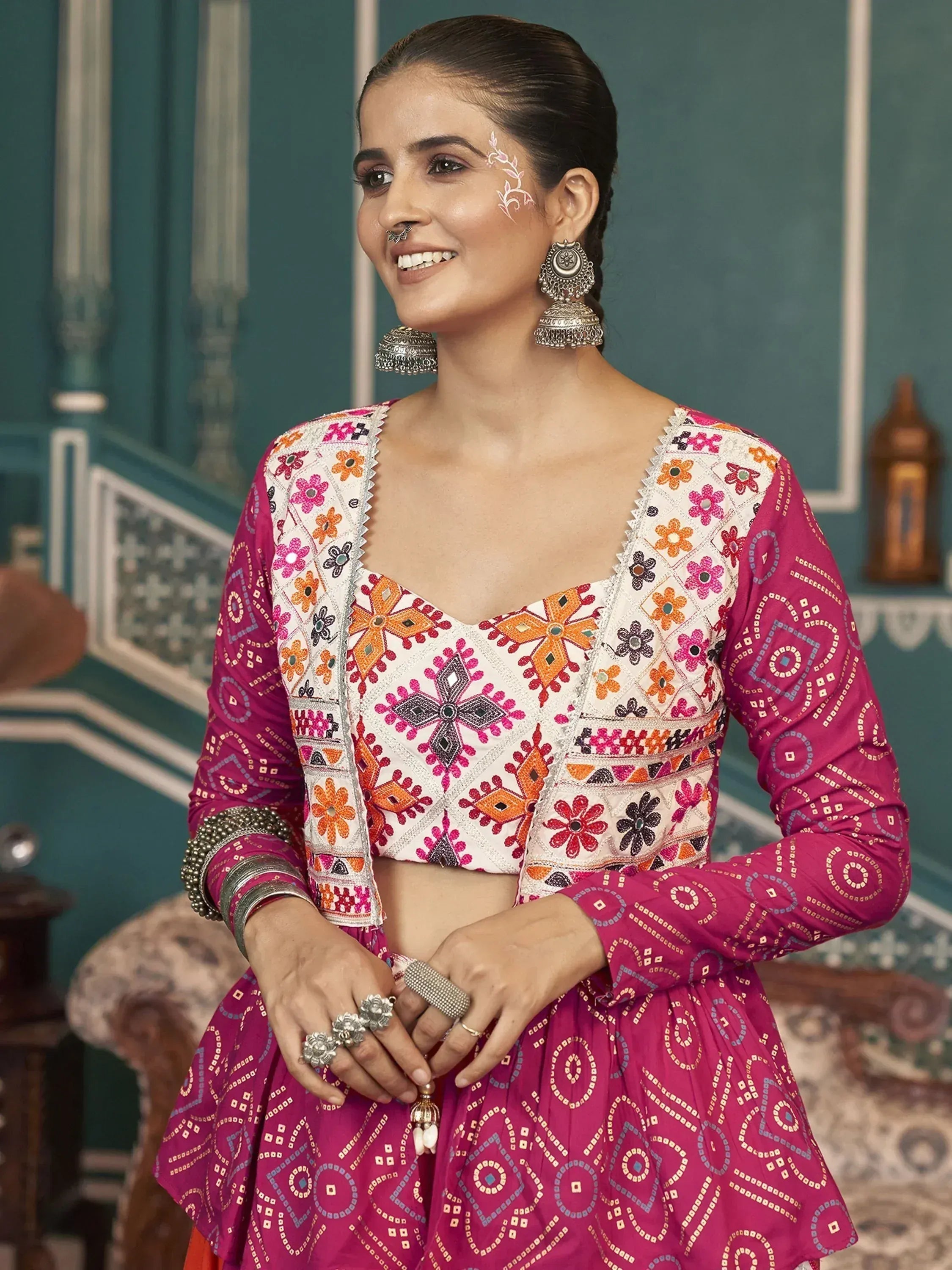 Woman in vibrant pink embroidered lehenga choli with floral mirror work, traditional Indian ethnic wear