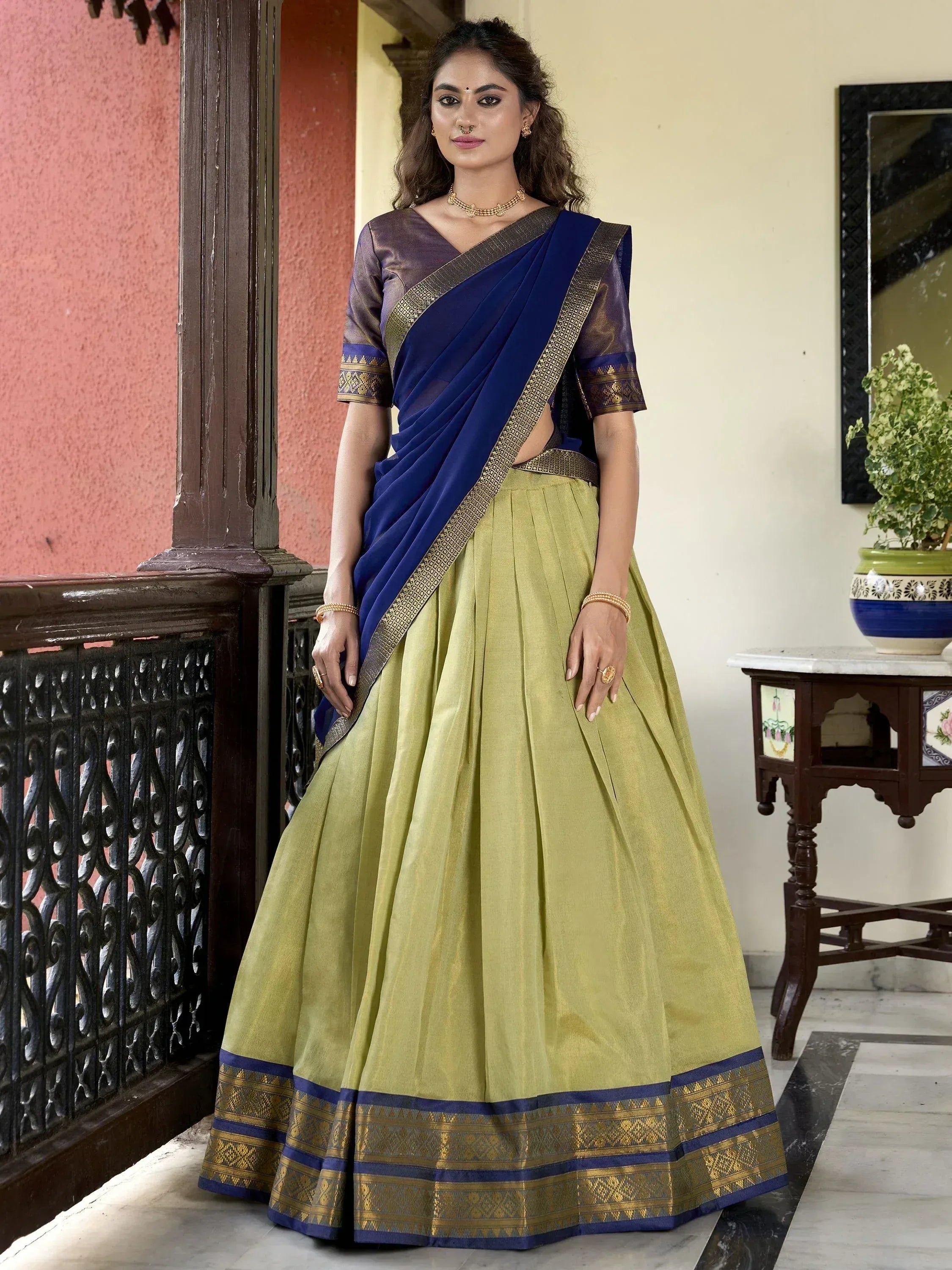 Woman in blue saree with gold border and olive green lehenga, traditional Indian ethnic wear