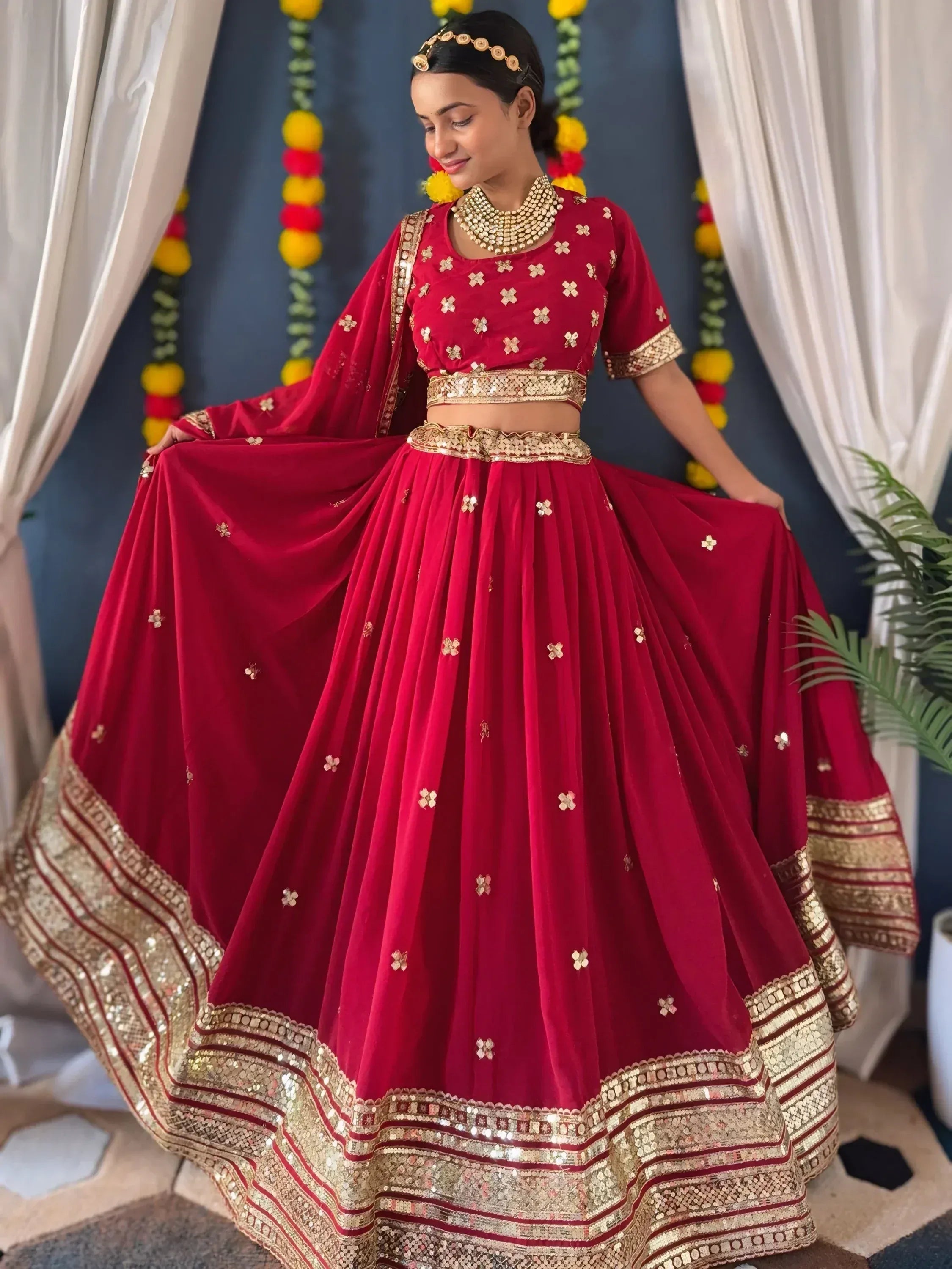 Red velvet lehenga choli with gold embroidery and mirror work, perfect for Indian weddings and festive occasions.