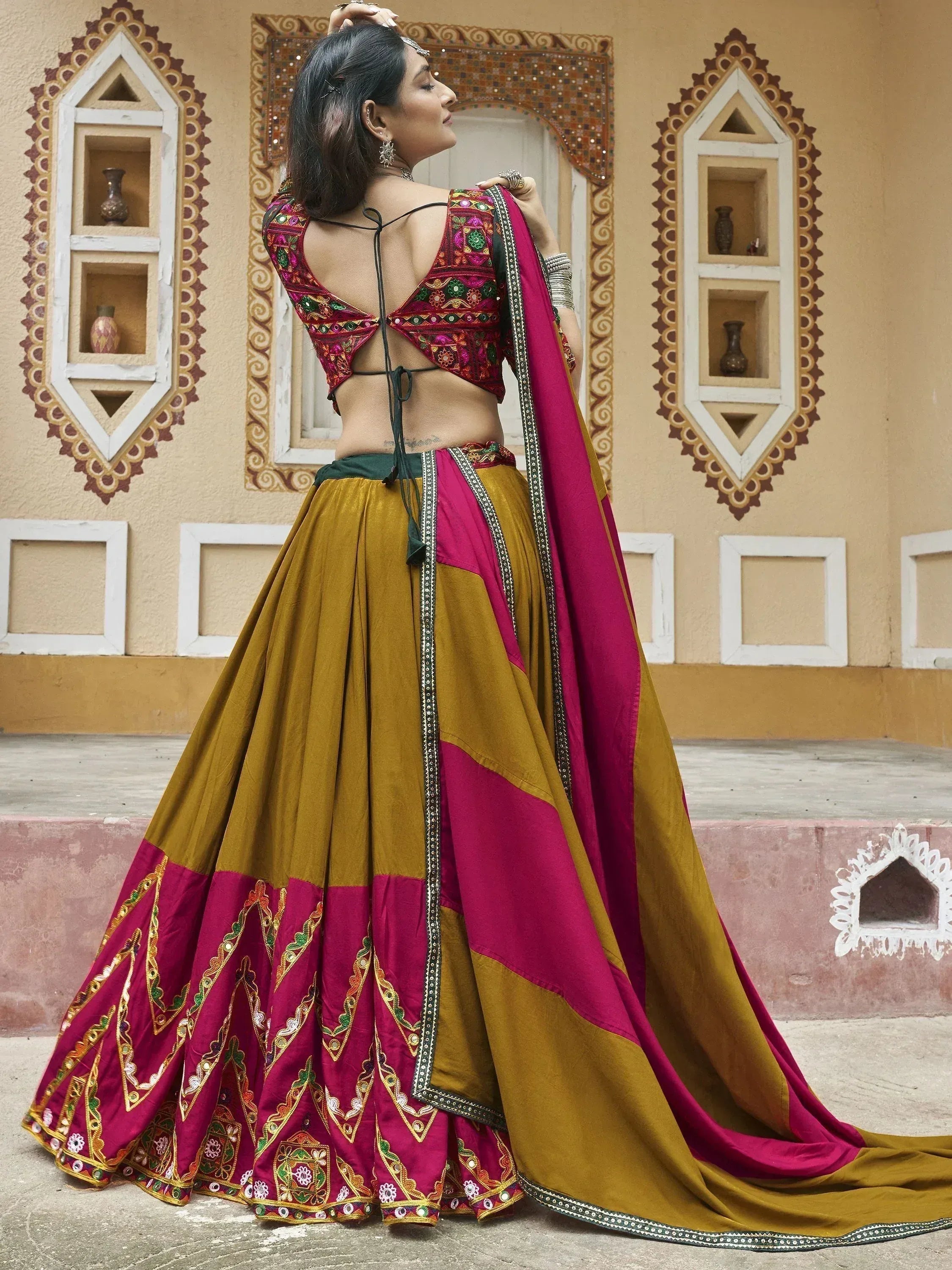 Woman in maroon and mustard ethnic lehenga choli with mirror work, perfect for Indian weddings or festivals.