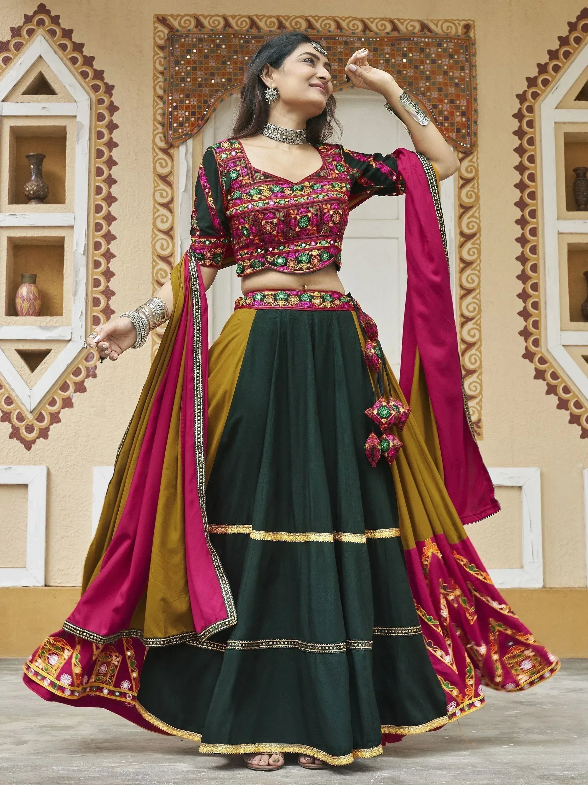 Woman in vibrant green and pink embroidered lehenga choli with mirror work, perfect for Indian ethnic occasions.