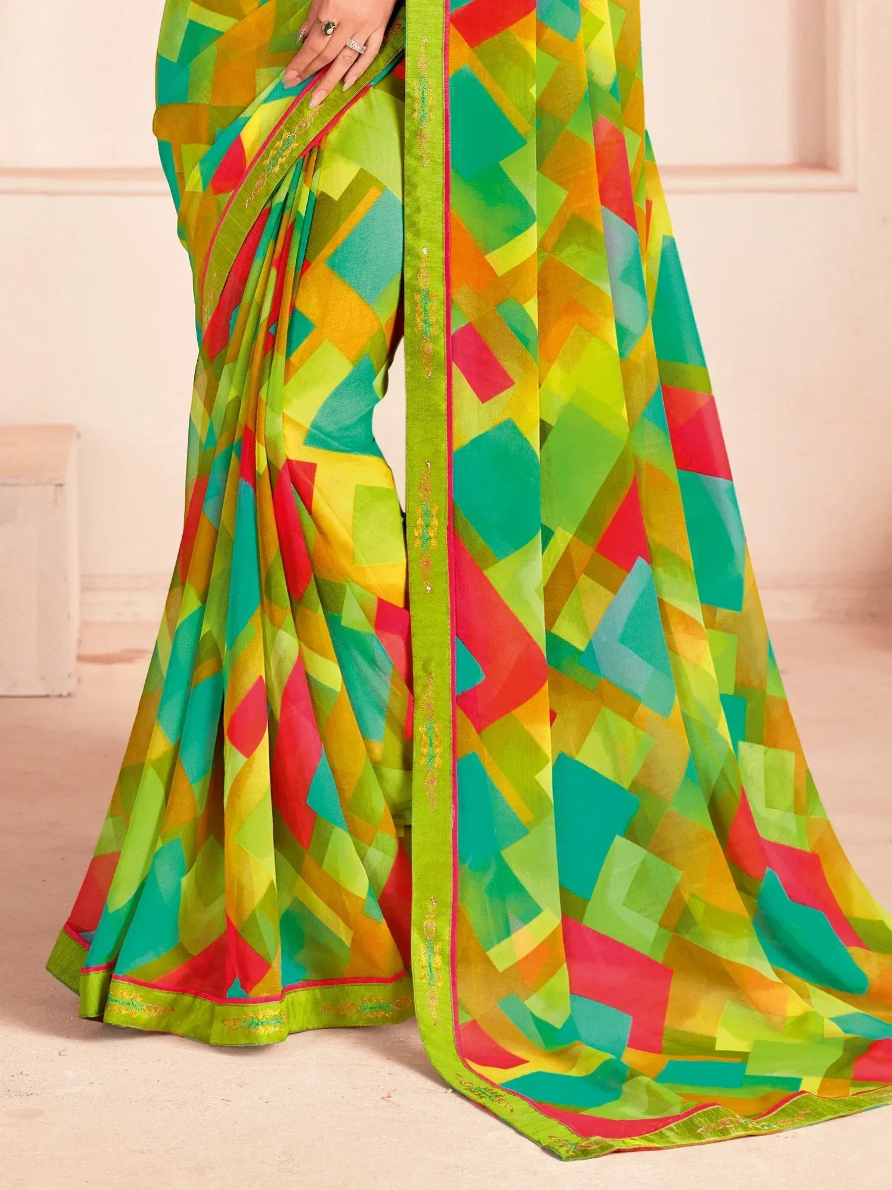 Vibrant geometric print saree in green, red, yellow, and teal with embroidered border, ideal for Indian ethnic wear.