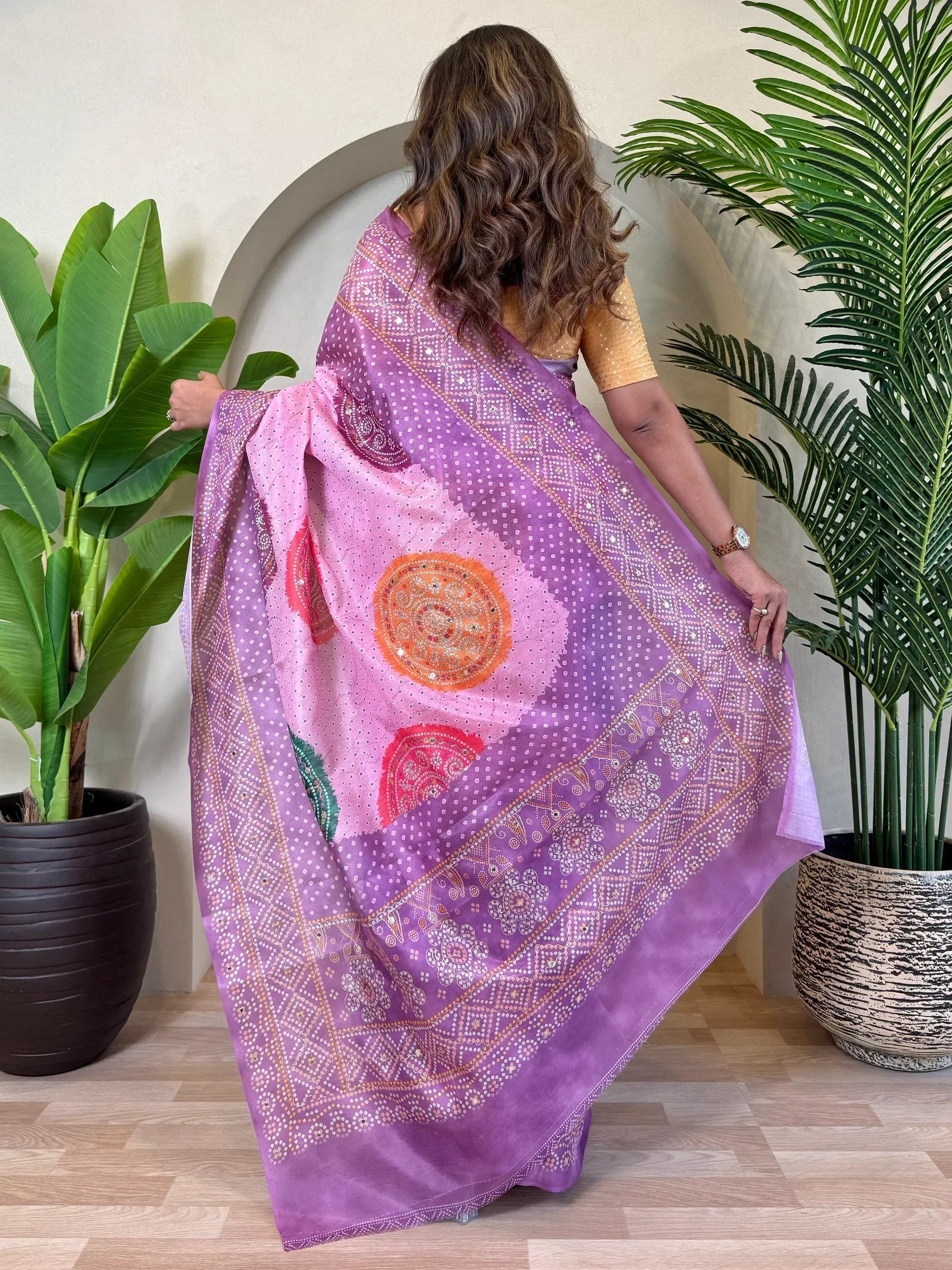 Purple and pink ethnic saree with mirror work and bandhani print, styled with gold blouse
