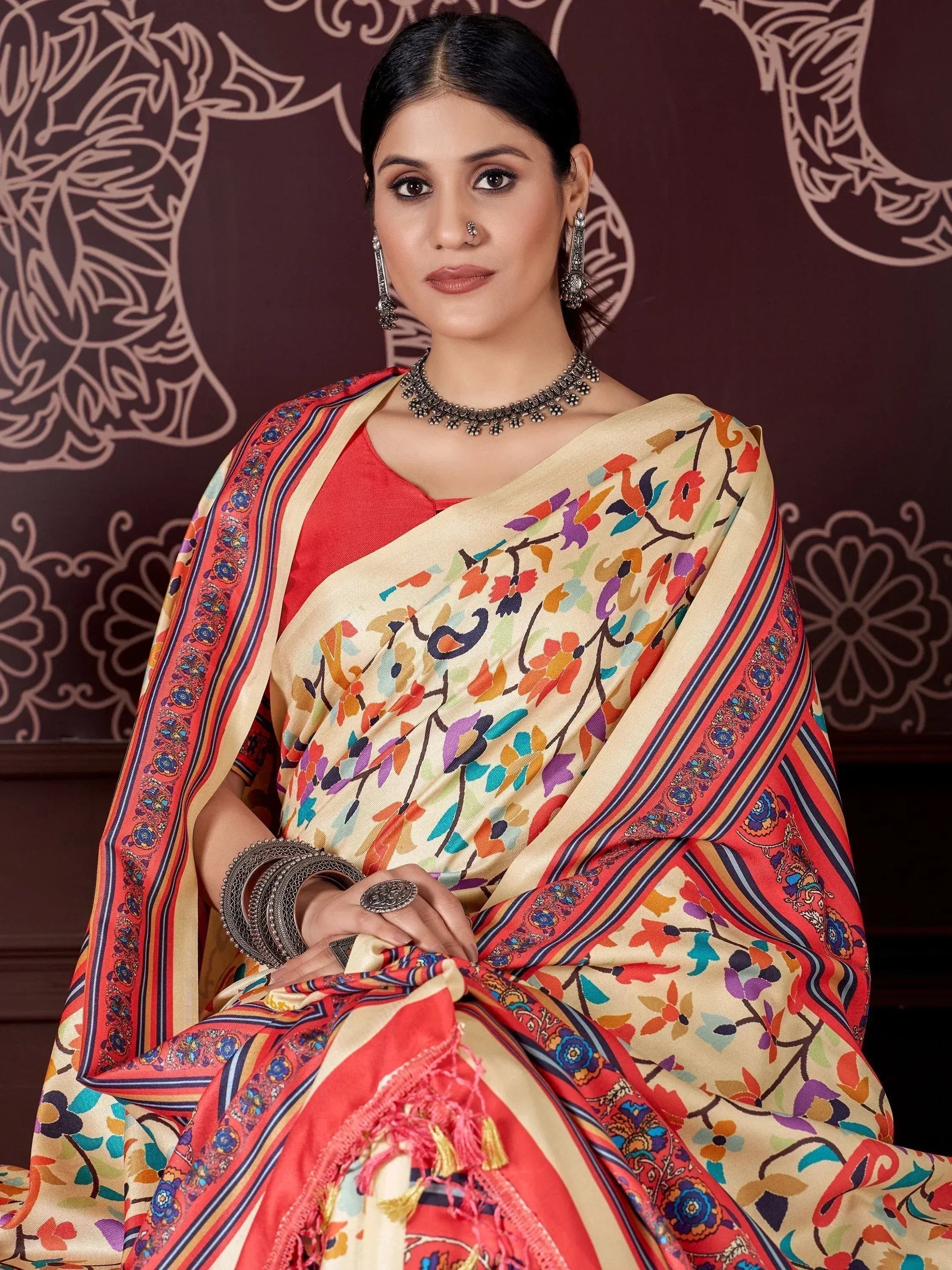 Woman in colorful floral saree with red blouse, ethnic jewelry, and tassels, perfect for Indian occasions
