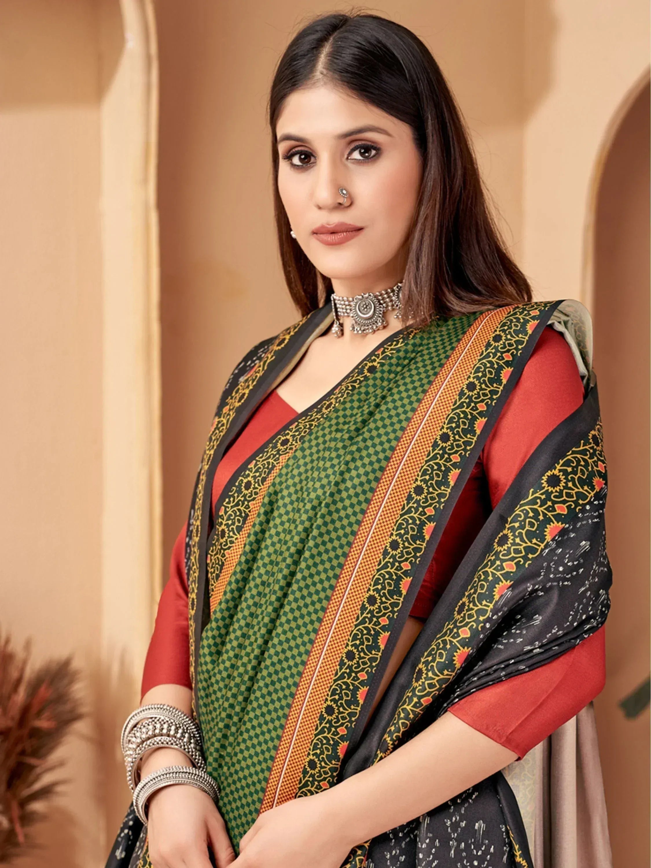 Woman in green checkered saree with black border and red blouse, styled with ethnic jewelry for traditional occasions.