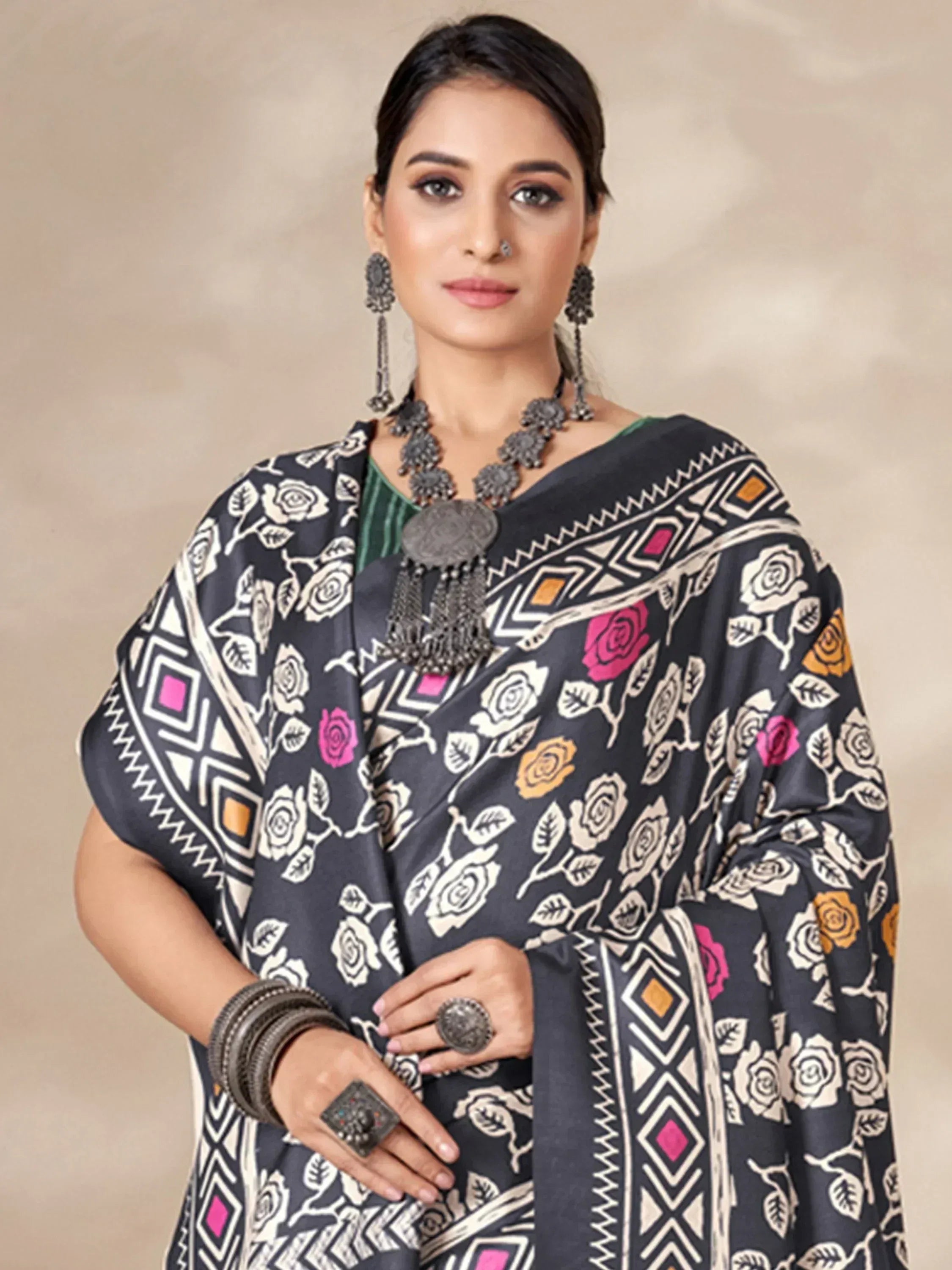 Woman in black floral print saree with geometric border, ethnic jewelry, green blouse