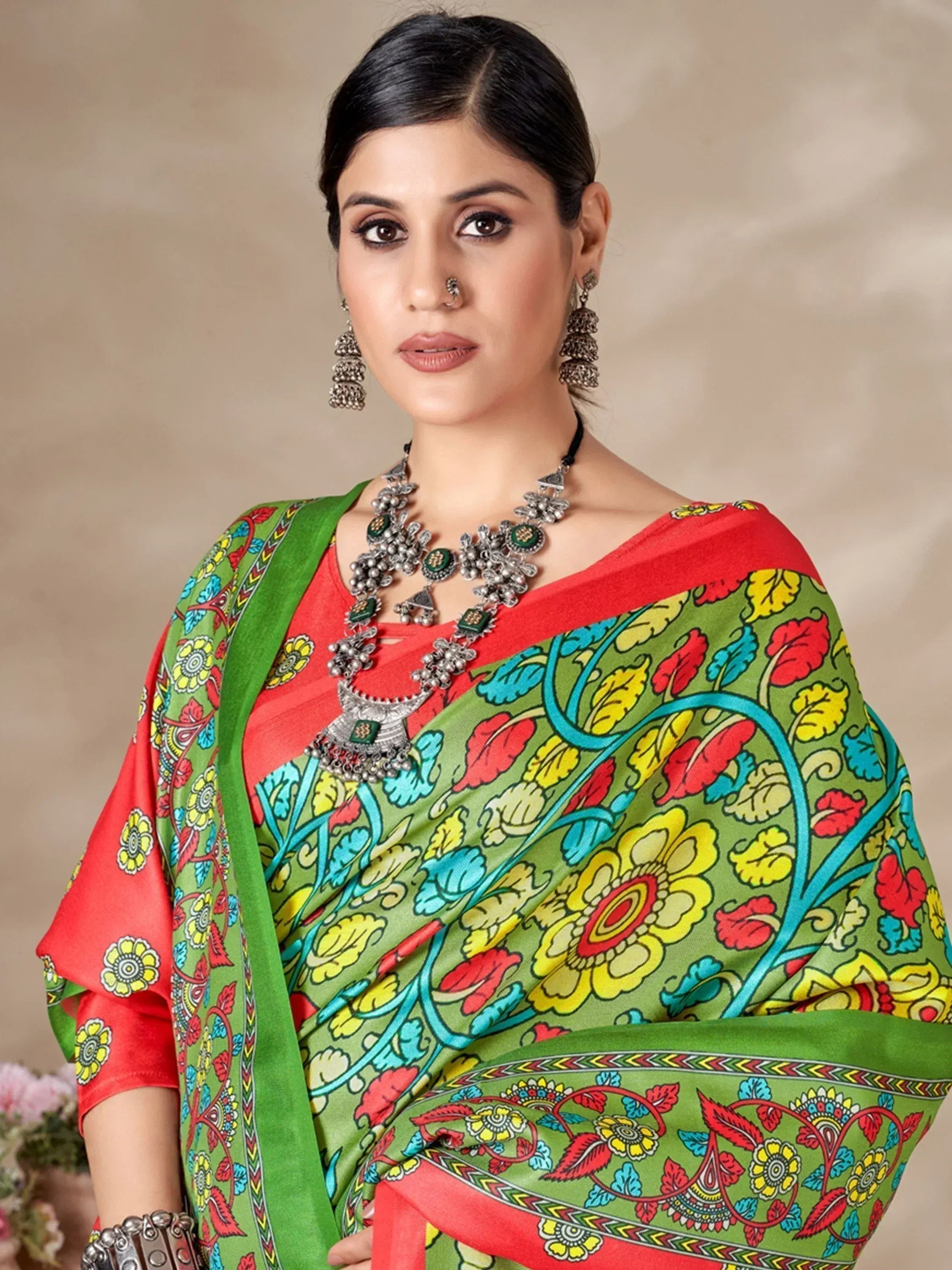 Woman in vibrant green and red floral printed saree with traditional jewelry, ethnic Indian wear