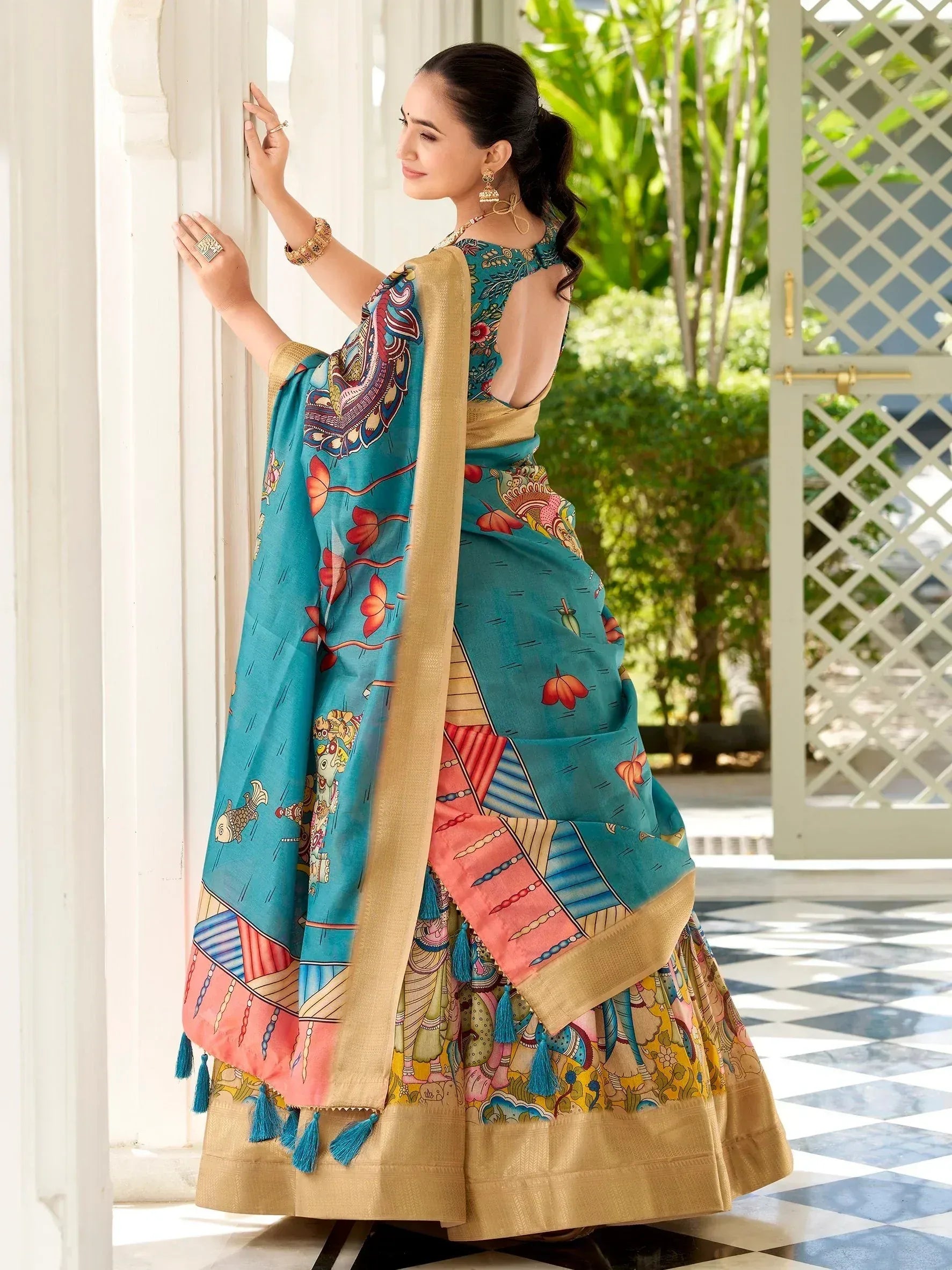 Woman in vibrant turquoise printed saree with gold border and tassels, ethnic Indian wear