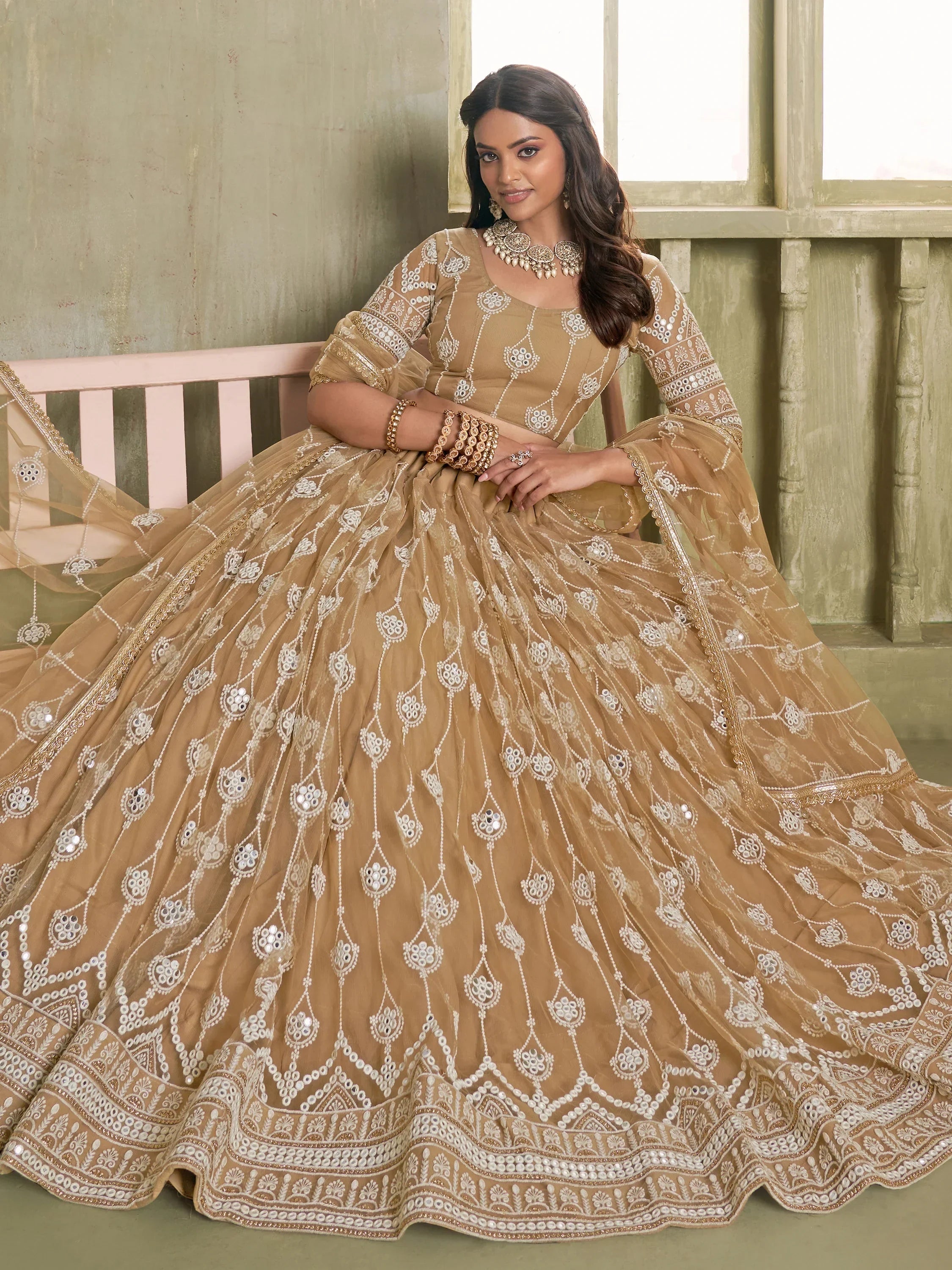 Elegant beige designer lehenga choli with intricate white embroidery and mirror work, perfect for Indian ethnic wear.