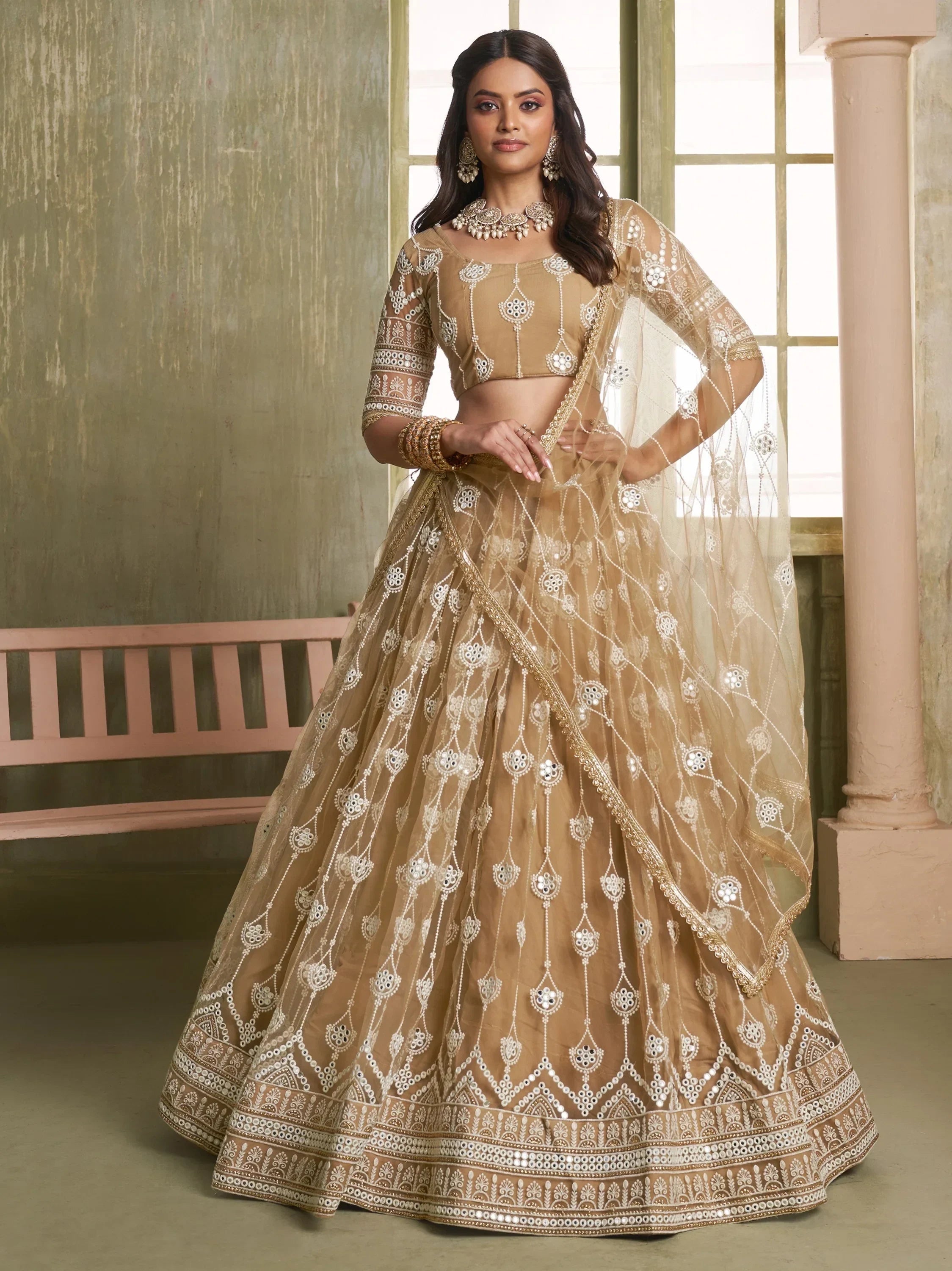 Beige designer lehenga choli with intricate mirror and thread embroidery, perfect for Indian weddings and festive occasions.