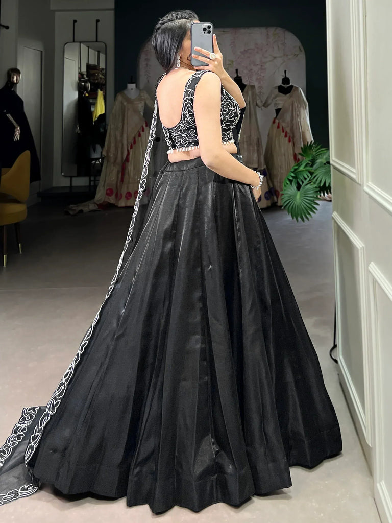 Black designer lehenga choli with white embroidery, back view in boutique