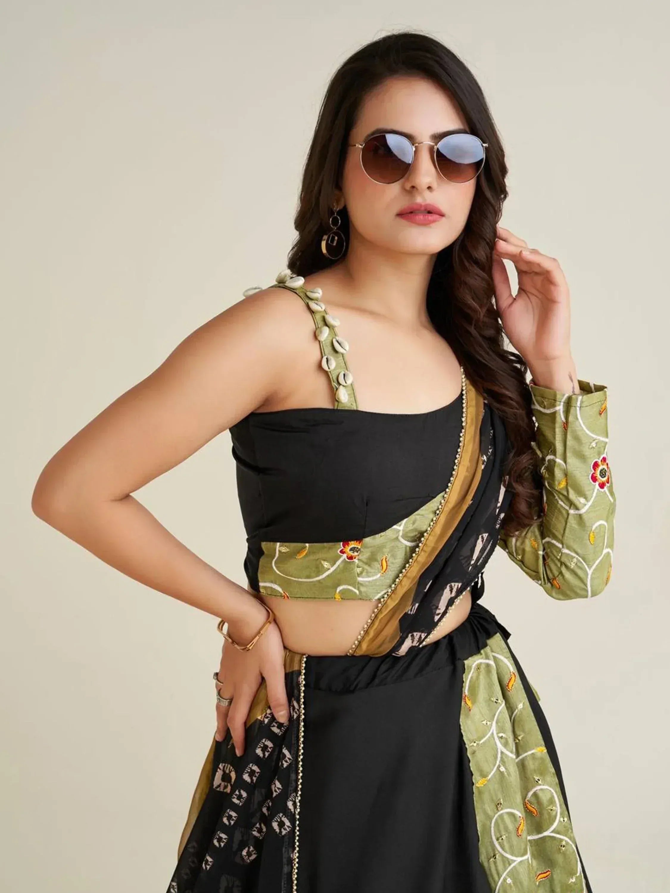 Black and olive green ethnic saree with shell-embellished straps and floral embroidery, styled with sunglasses.