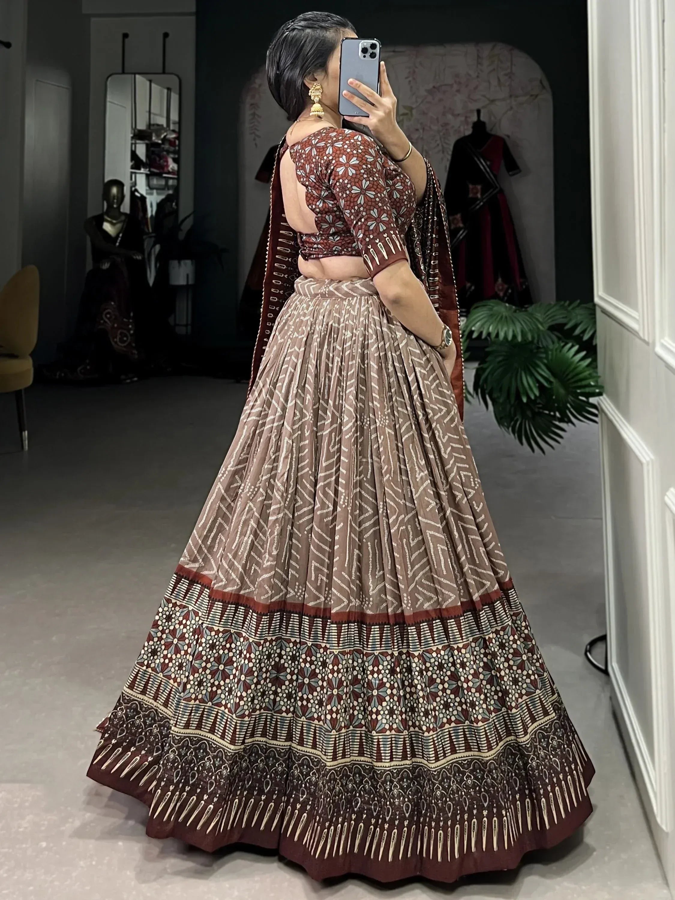 Woman in printed lehenga choli taking mirror selfie, ethnic Indian wear with floral and geometric patterns
