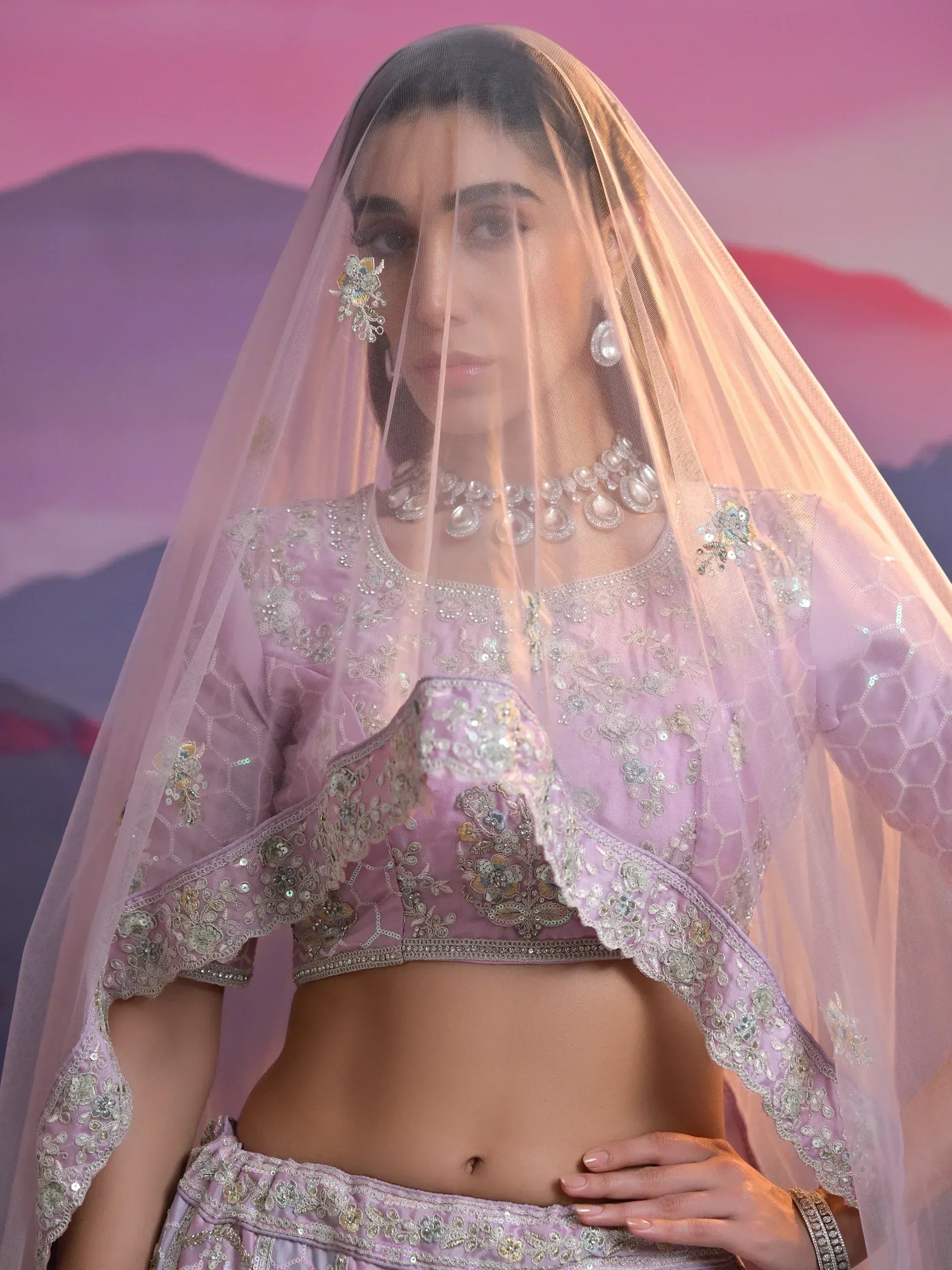 Elegant lavender lehenga choli with intricate embroidery, sheer dupatta, and pearl jewelry for Indian ethnic wear