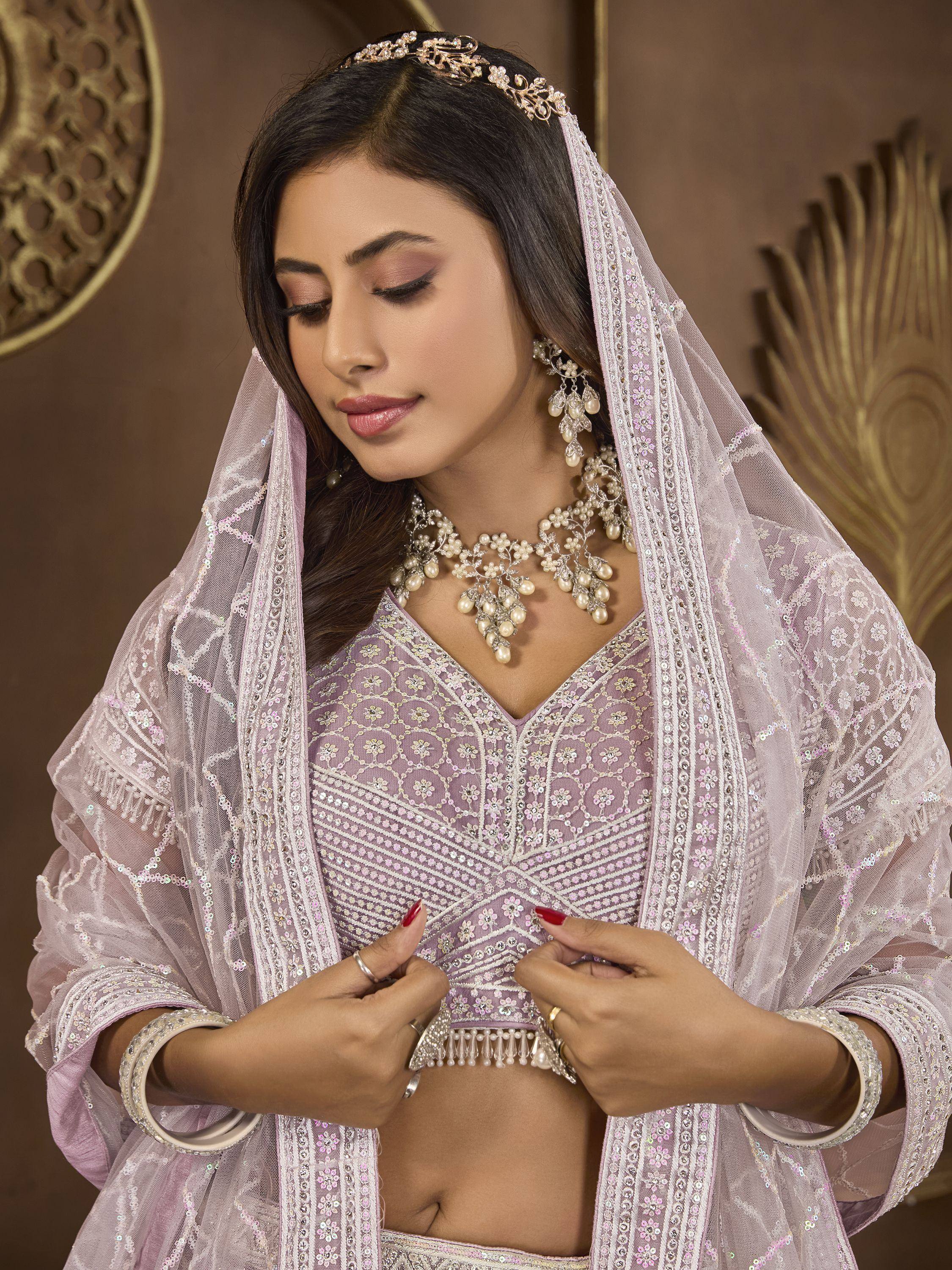 Elegant lavender lehenga choli with intricate embroidery, pearl jewelry, and matching dupatta for Indian ethnic wear.