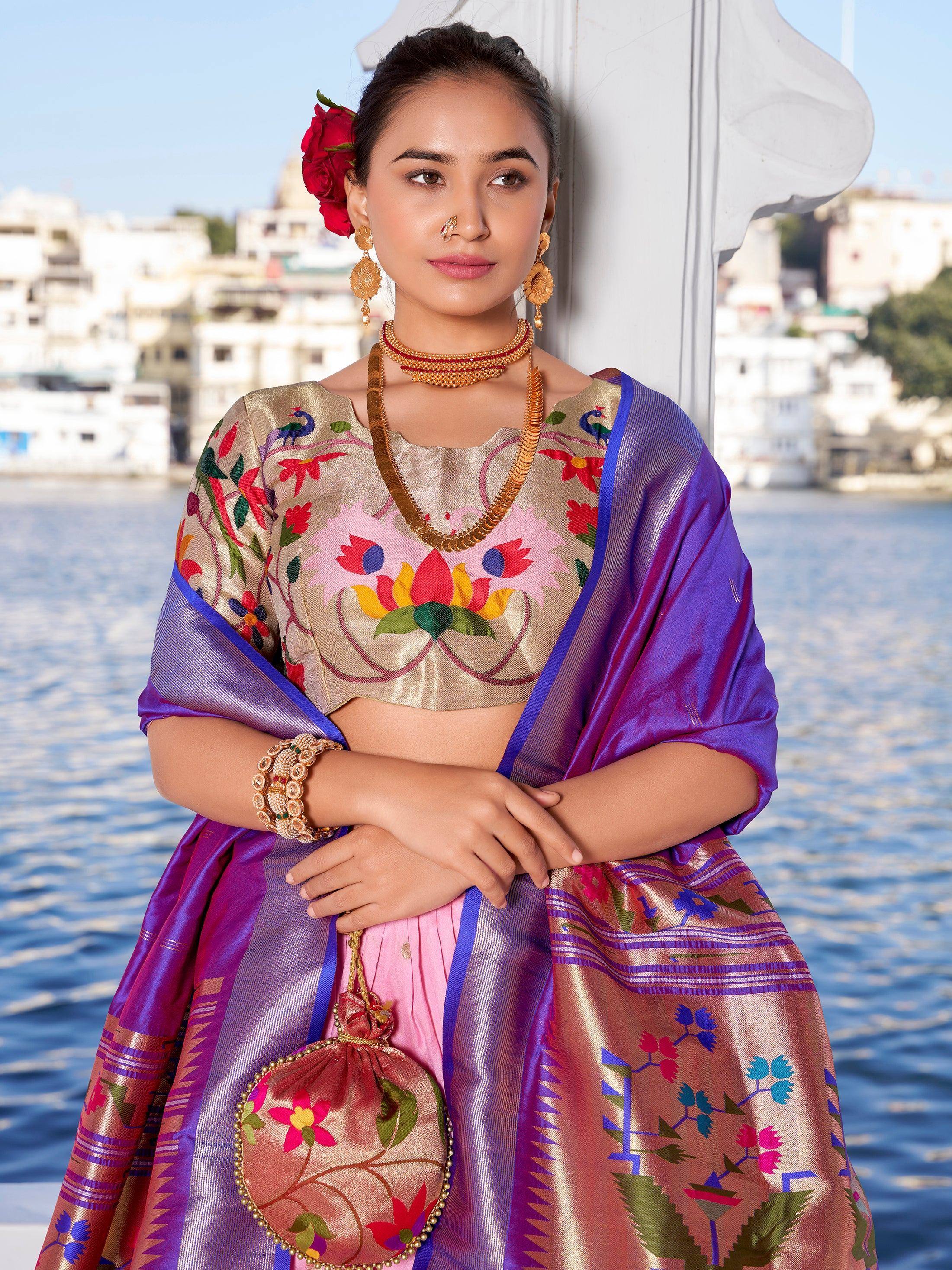 Woman in embroidered lehenga choli with purple dupatta, floral motifs, gold jewelry, by water