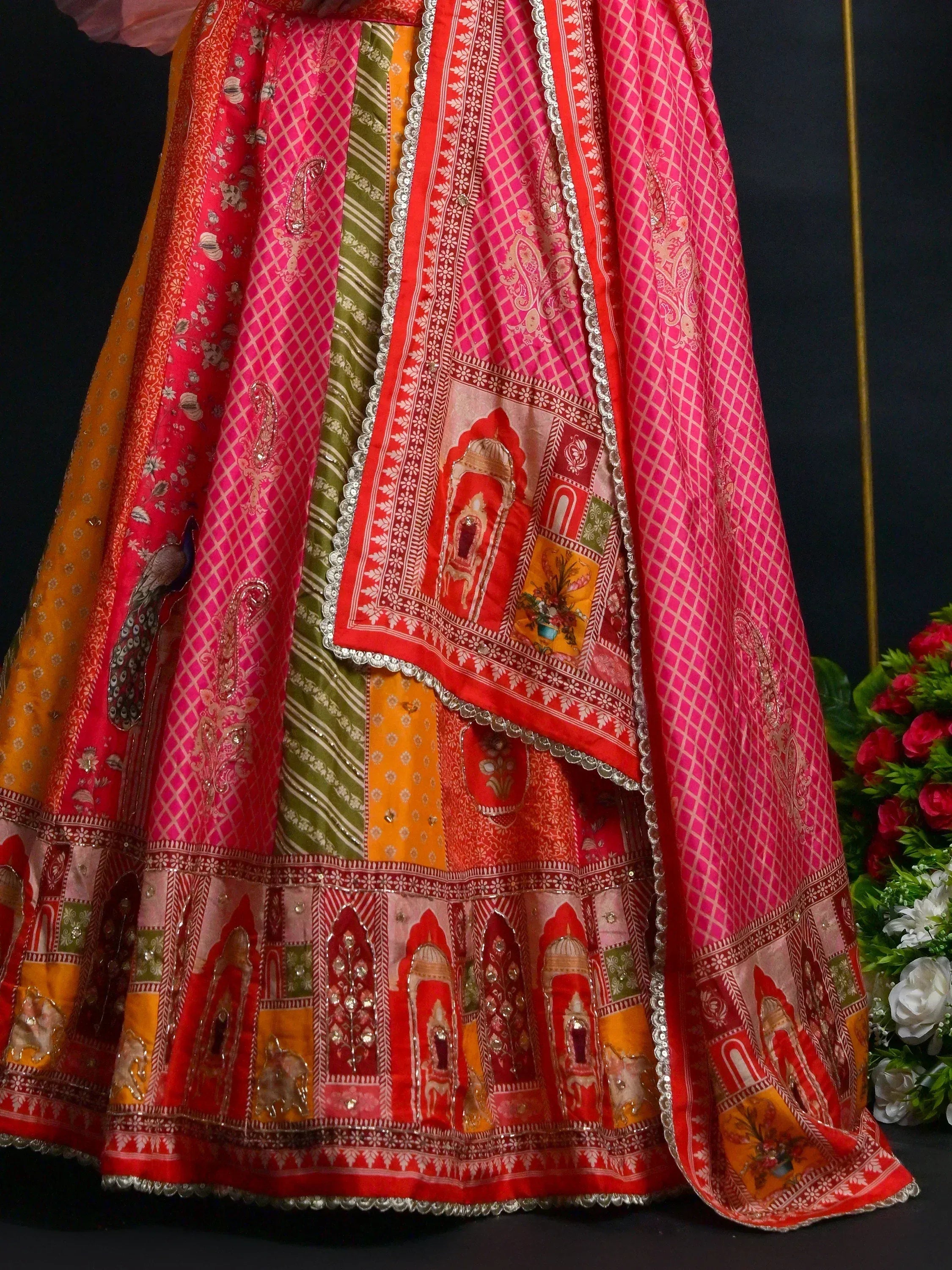 Vibrant pink and orange patchwork lehenga with peacock motifs and traditional Indian prints, perfect for festive occasions.