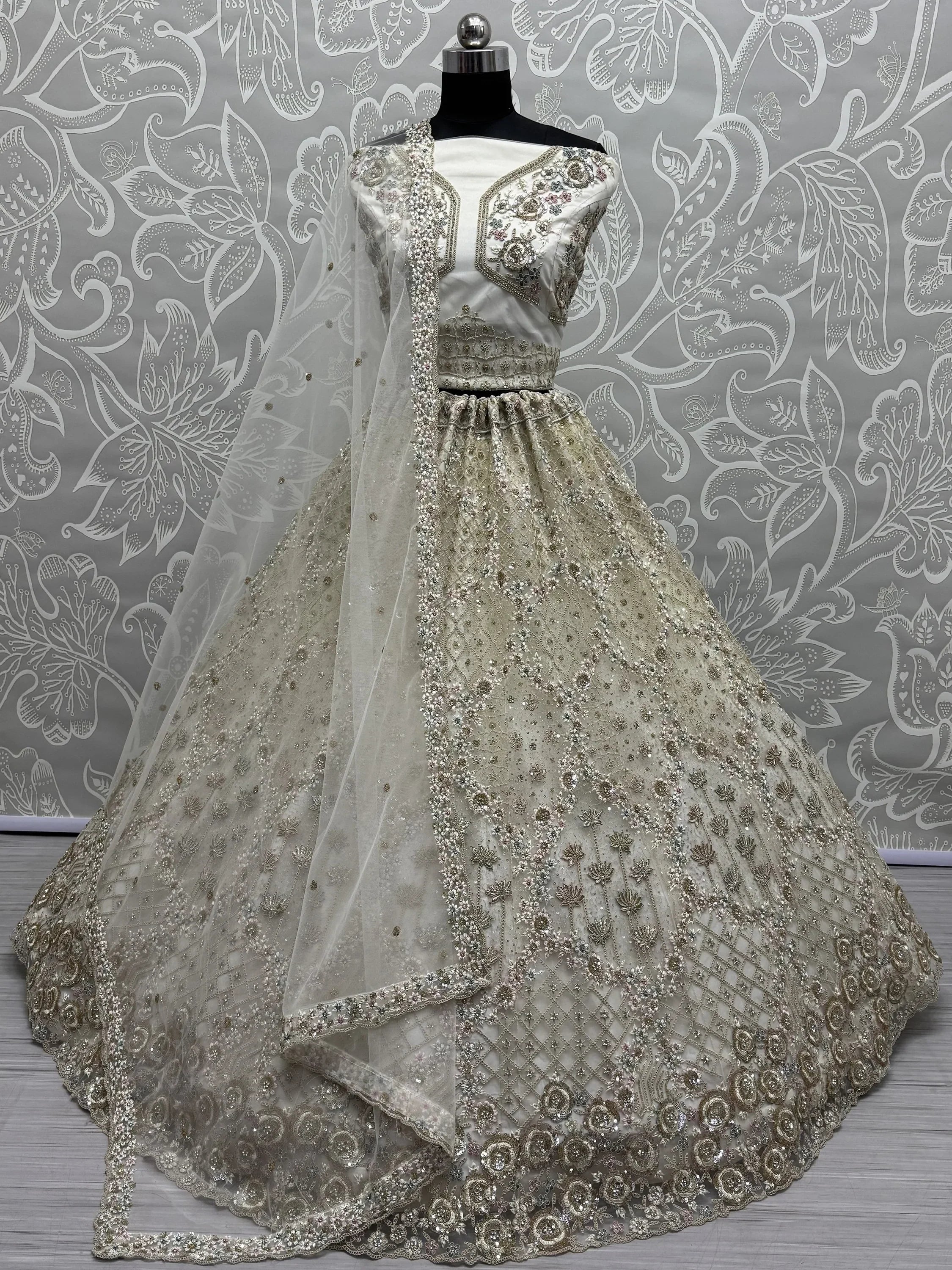 Elegant ivory lehenga choli with heavy embroidery and sheer dupatta, perfect for Indian weddings and festive occasions.