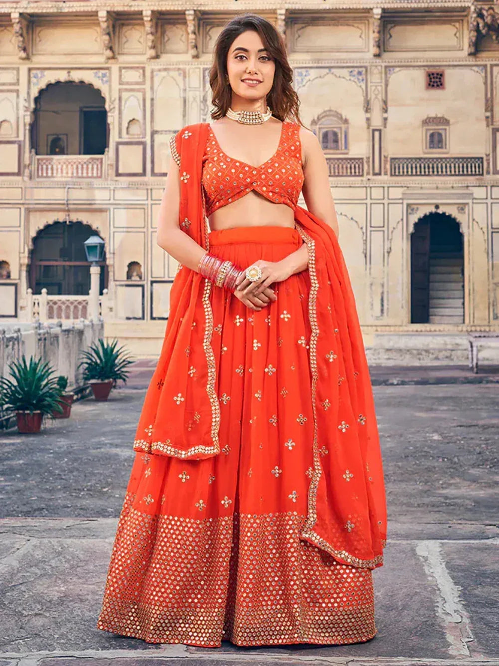 Vibrant orange lehenga choli with gold embroidery, perfect for Indian weddings and festive occasions