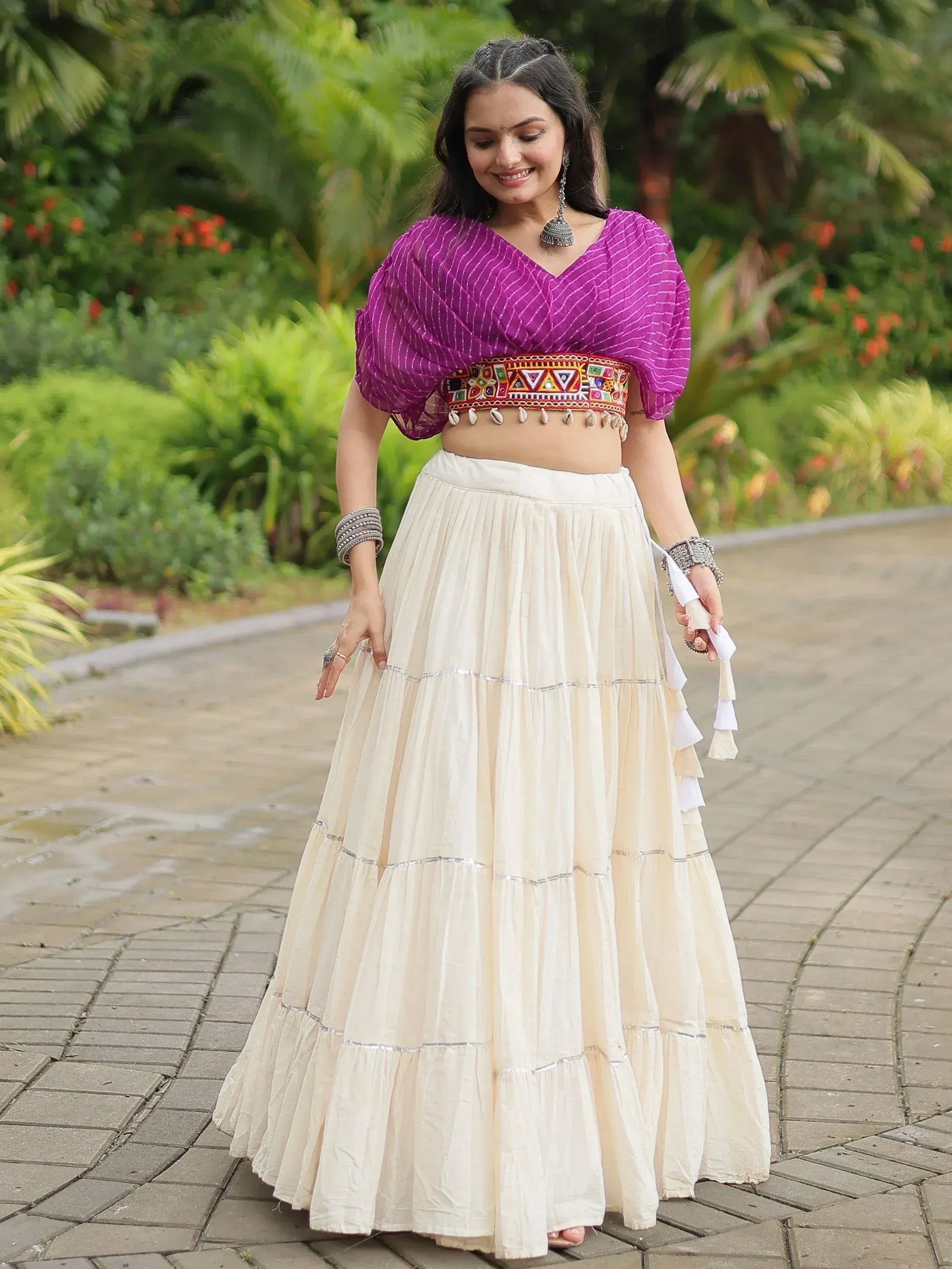 Woman in purple striped crop top with embroidered belt and cream tiered skirt, ethnic Indian wear