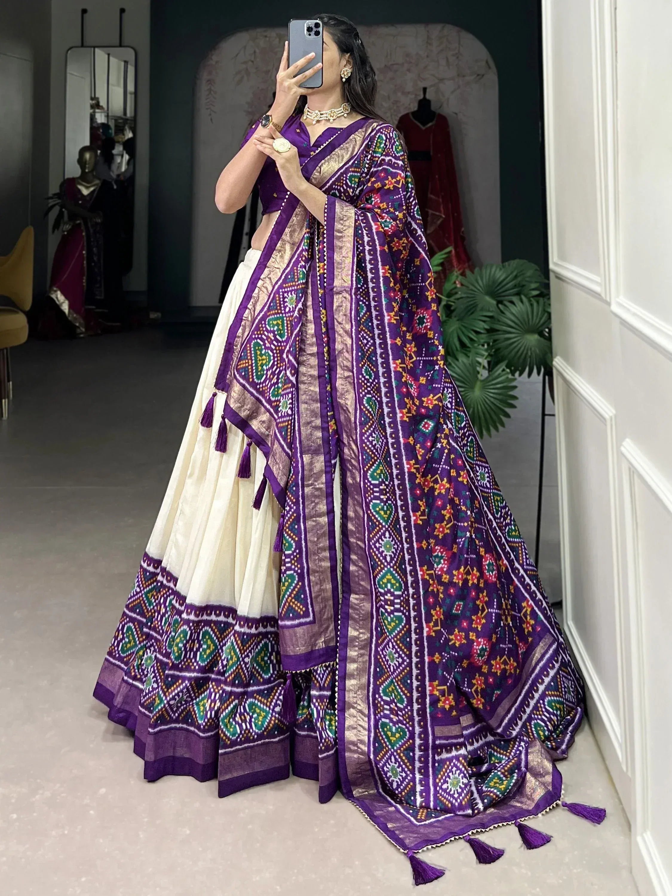 Purple and cream ethnic lehenga choli with intricate geometric print and tassels, perfect for festive occasions.
