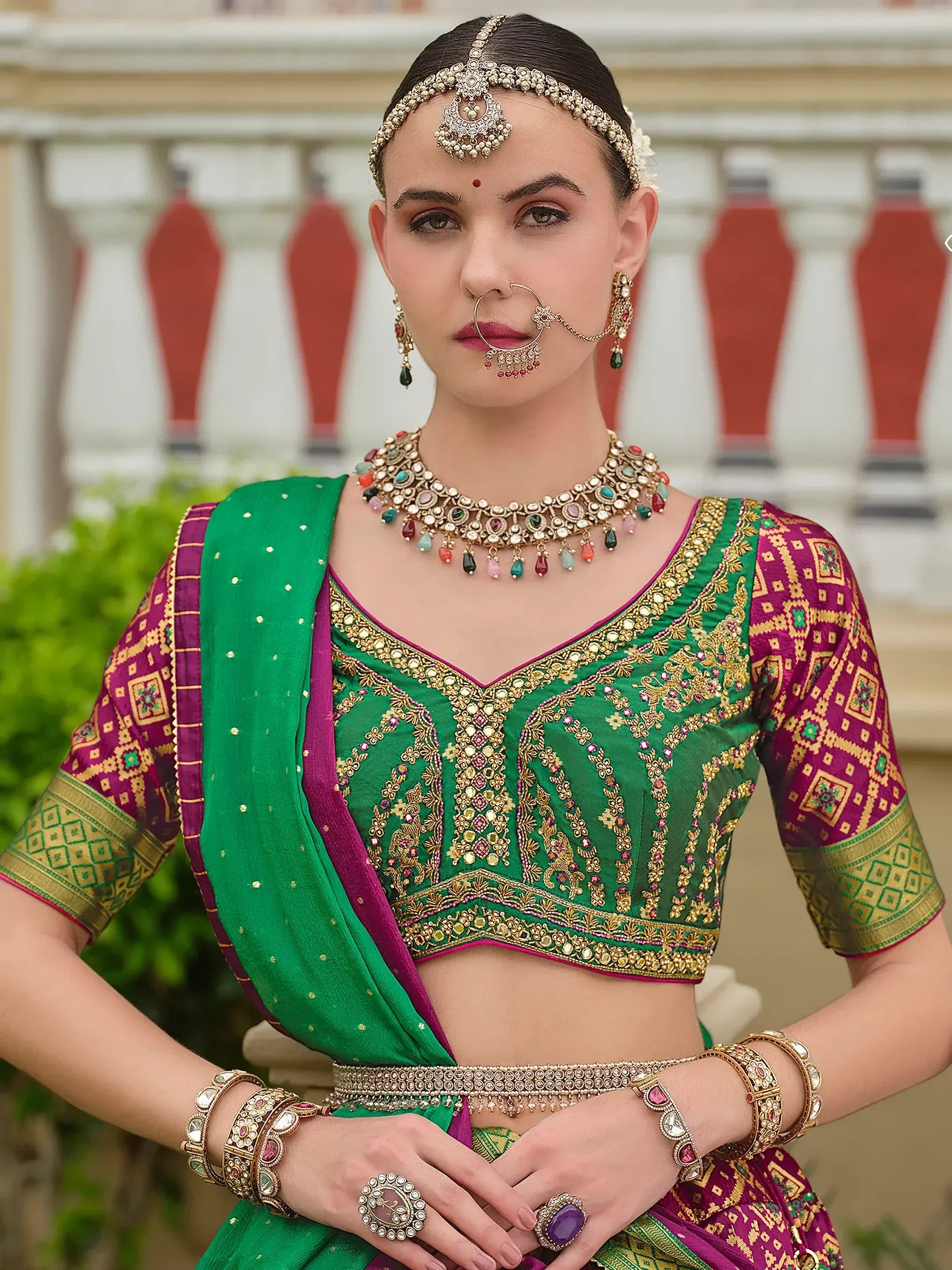Green and purple designer lehenga choli with gold embroidery, traditional Indian jewelry, and nose ring
