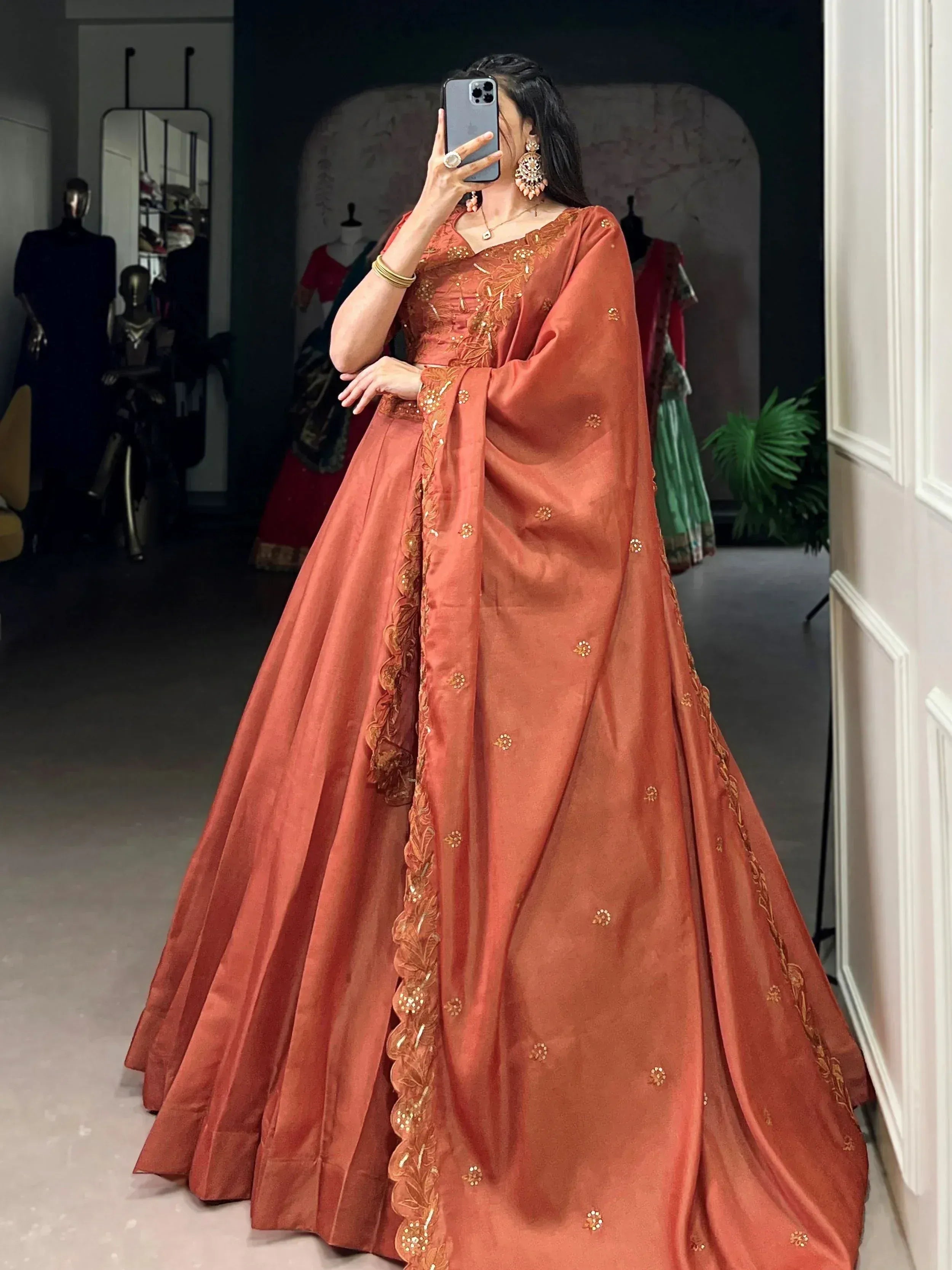 Woman in rust orange designer lehenga choli with gold embroidery, perfect for Indian ethnic wear events