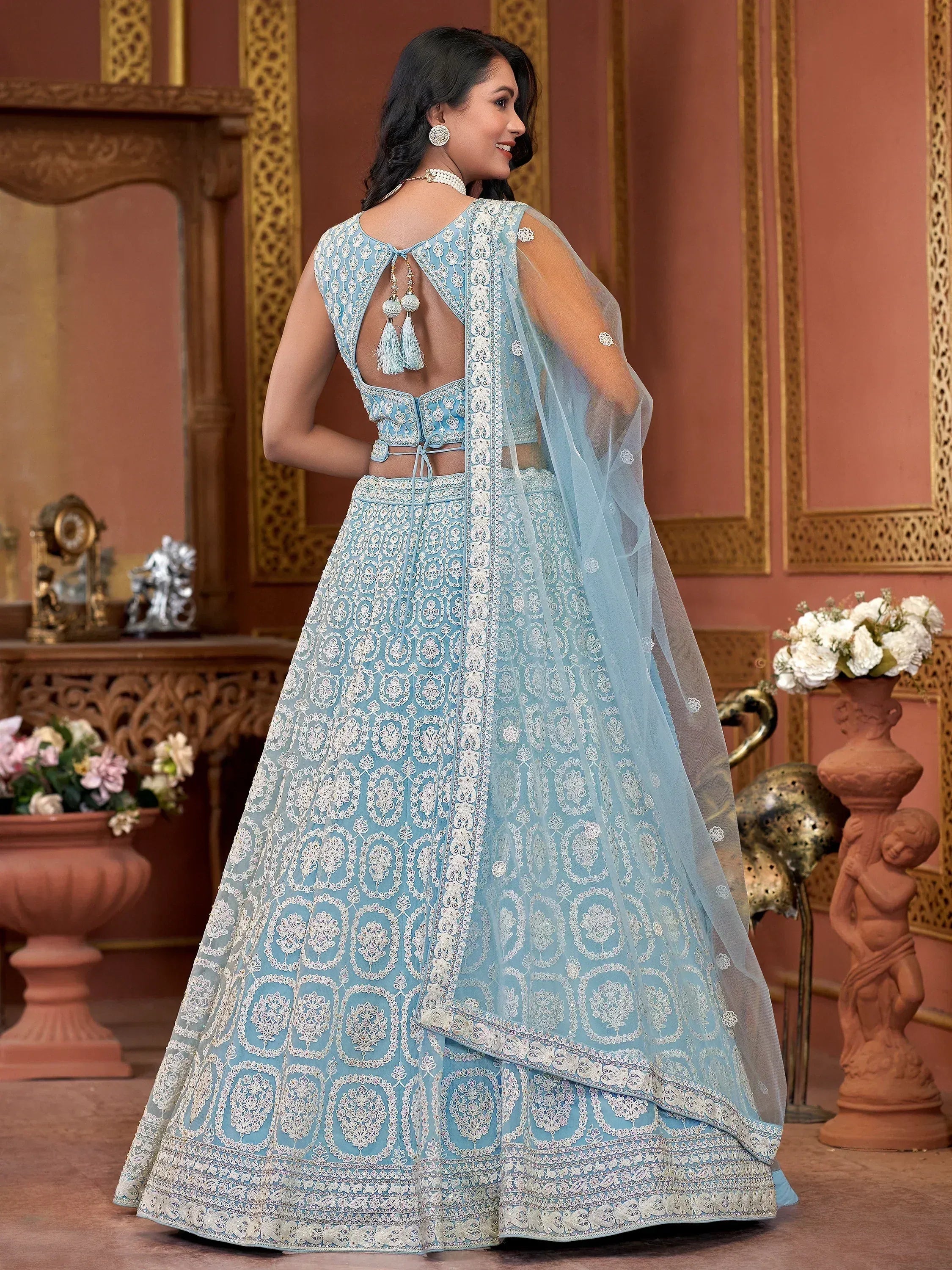 Light blue embroidered lehenga choli with back cutout and tassels, perfect for Indian weddings or festive occasions.