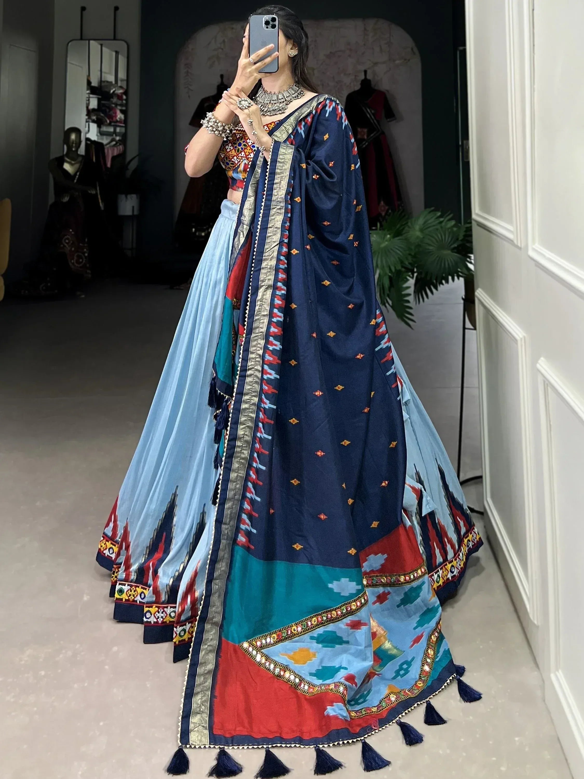 Woman in vibrant blue and multicolor embroidered lehenga choli with tassels, perfect for Indian ethnic wear