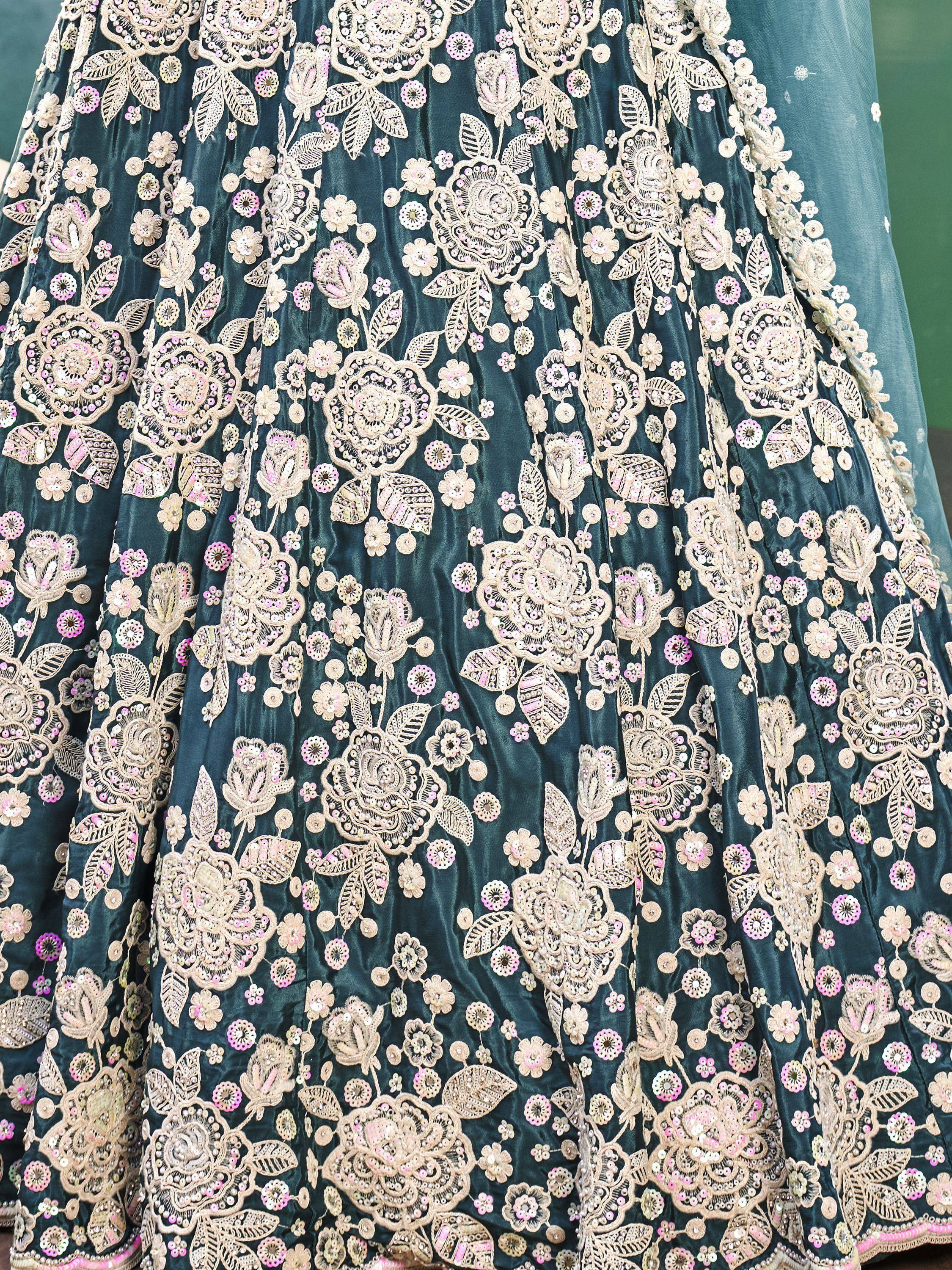 Teal velvet lehenga with intricate gold and pink floral embroidery and sequins, perfect for Indian ethnic wear.