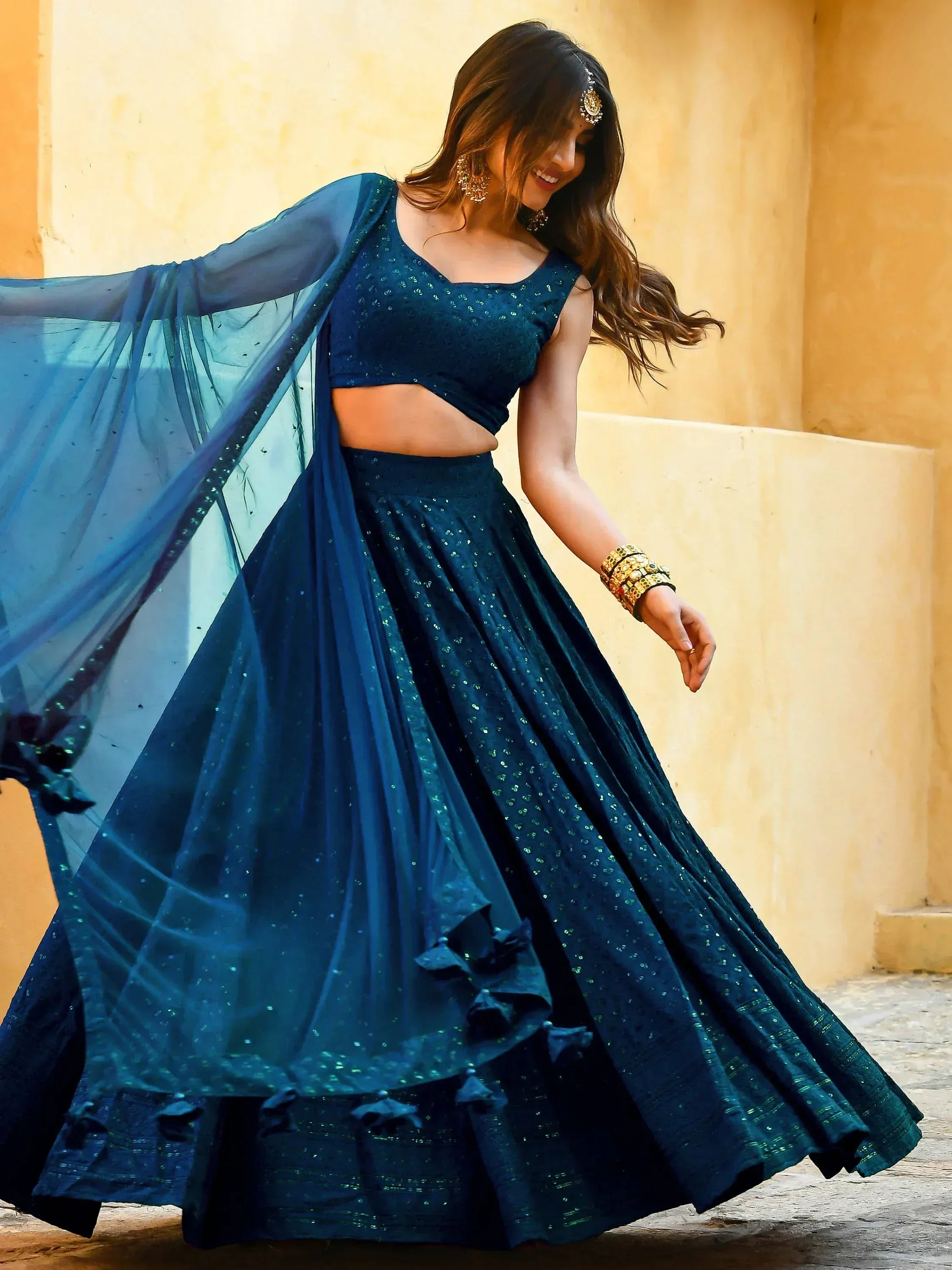 Woman in elegant navy blue lehenga choli with sheer dupatta, perfect for Indian ethnic wear events