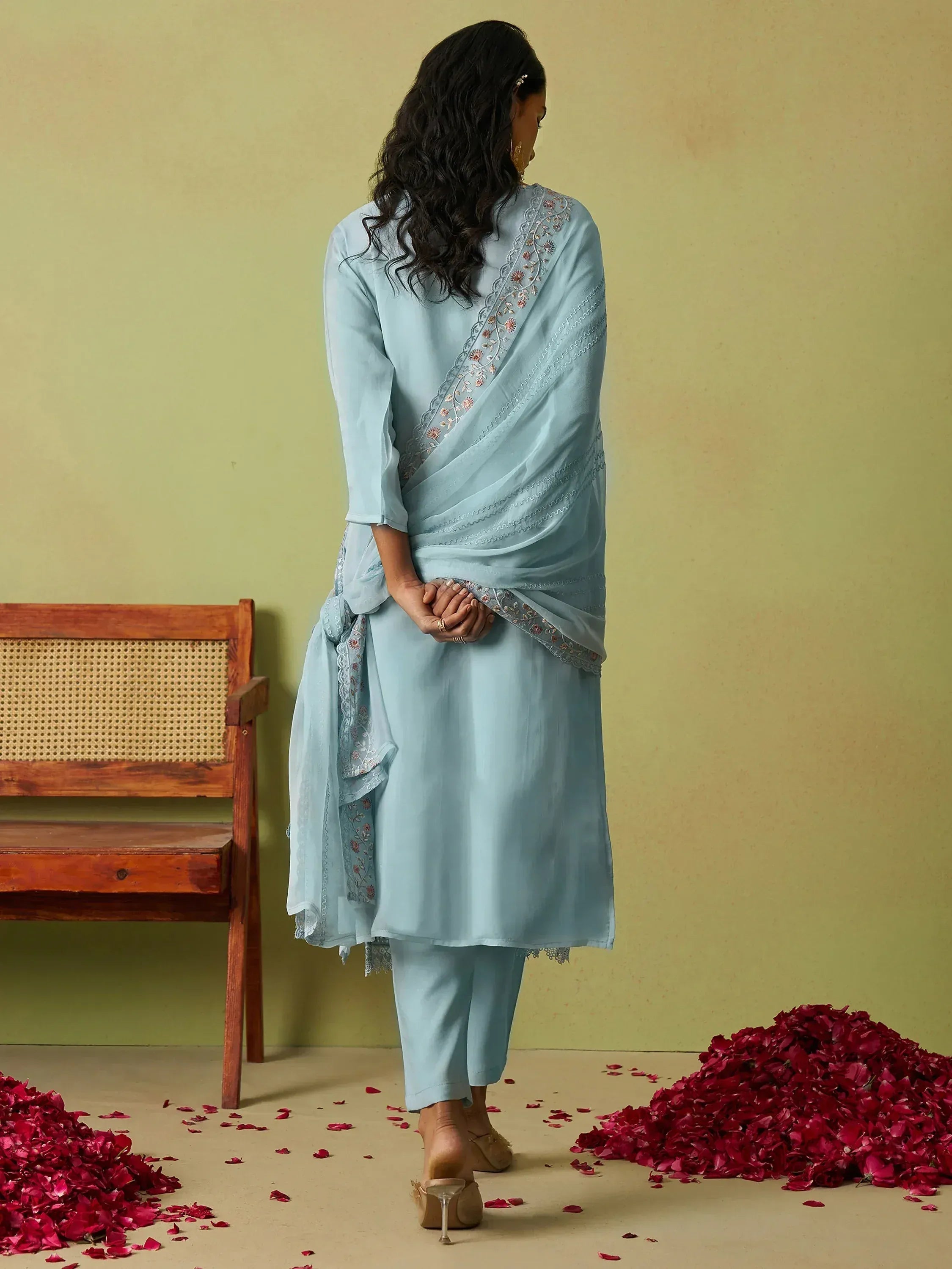 Light blue embroidered salwar kameez with dupatta, styled with rose petals and wooden bench