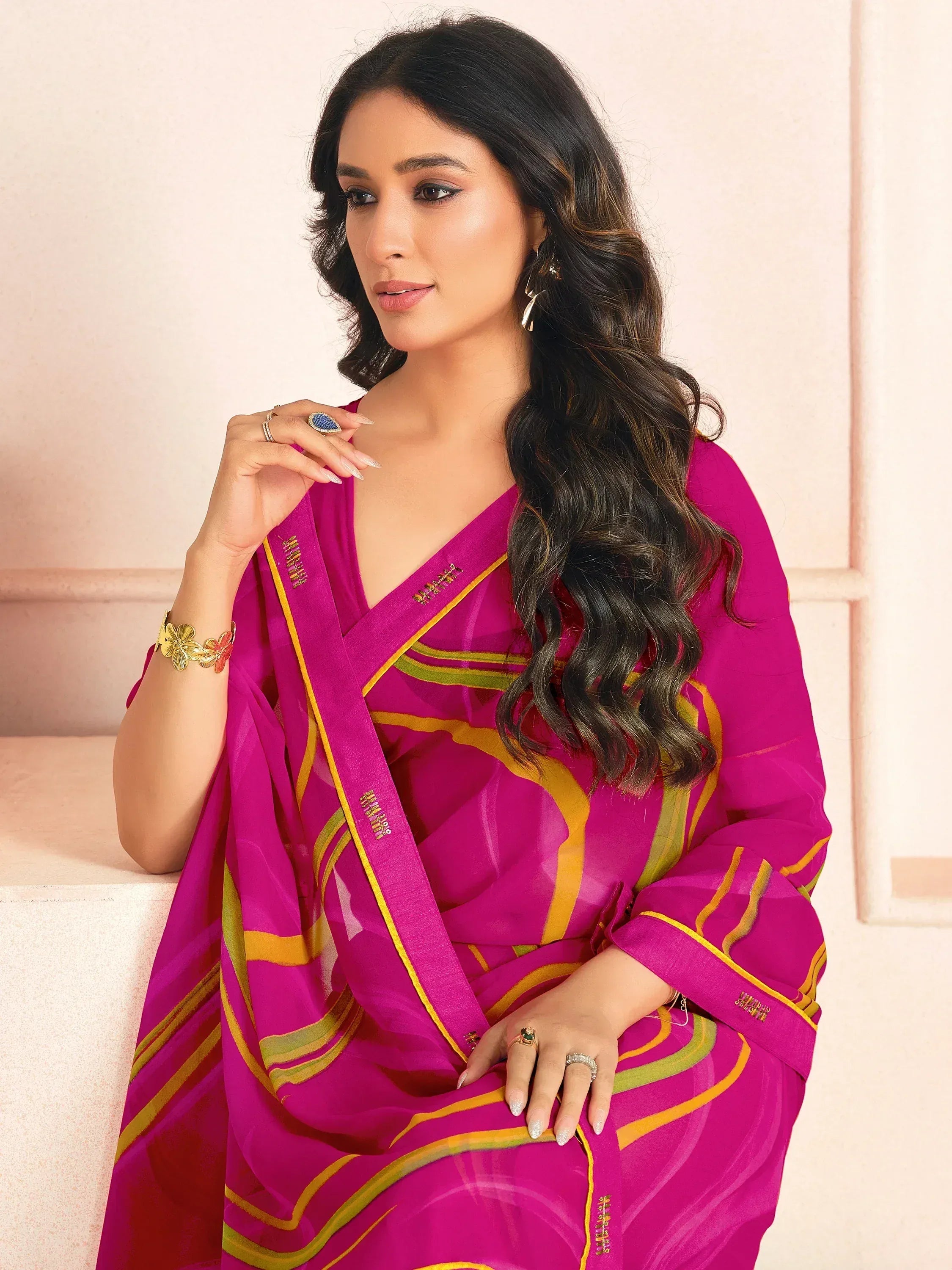 Vibrant magenta saree with gold and green stripes, styled with elegant jewelry for ethnic wear