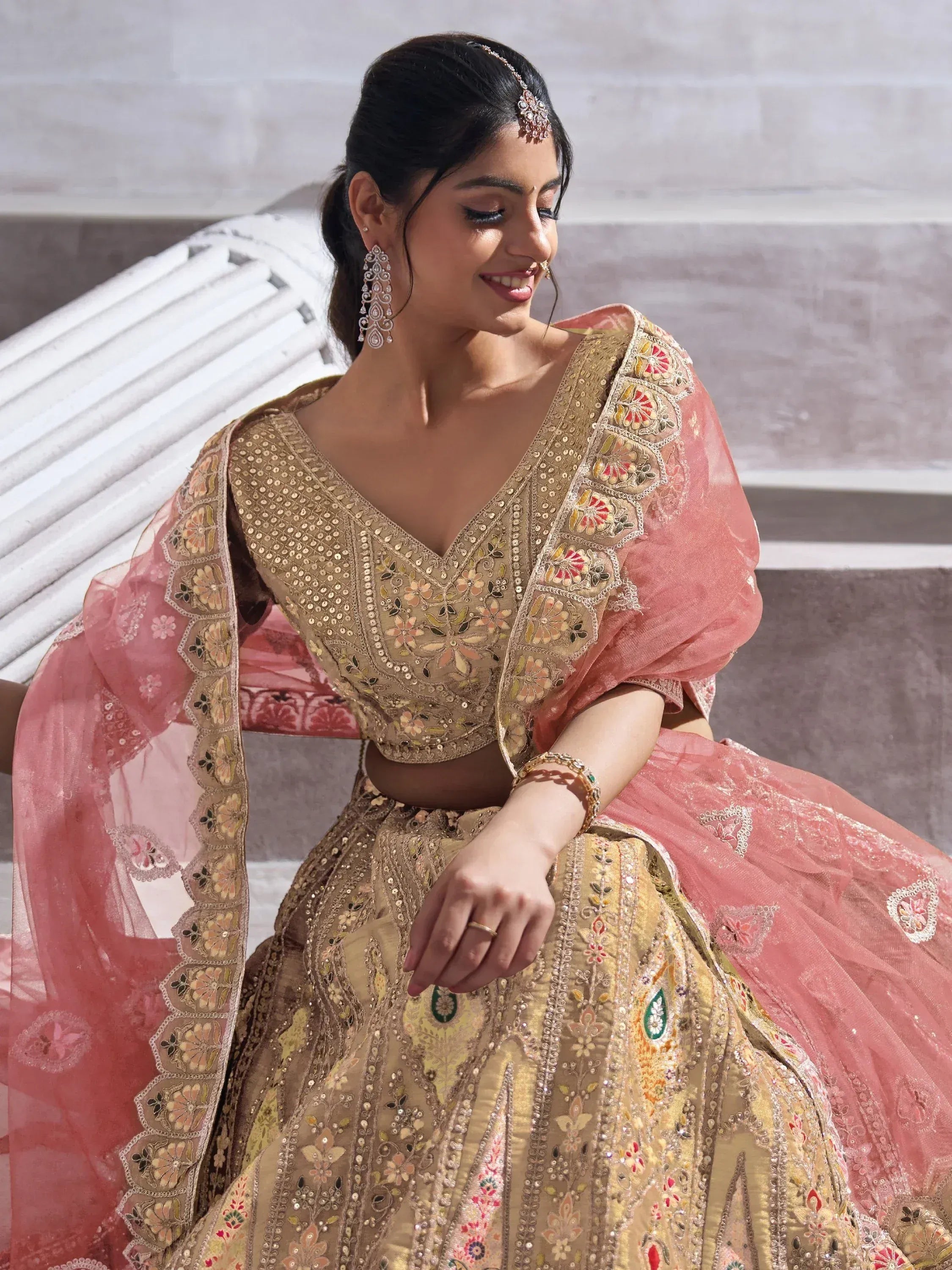 Elegant gold and pink embroidered lehenga choli with floral motifs, perfect for Indian weddings and festive occasions.