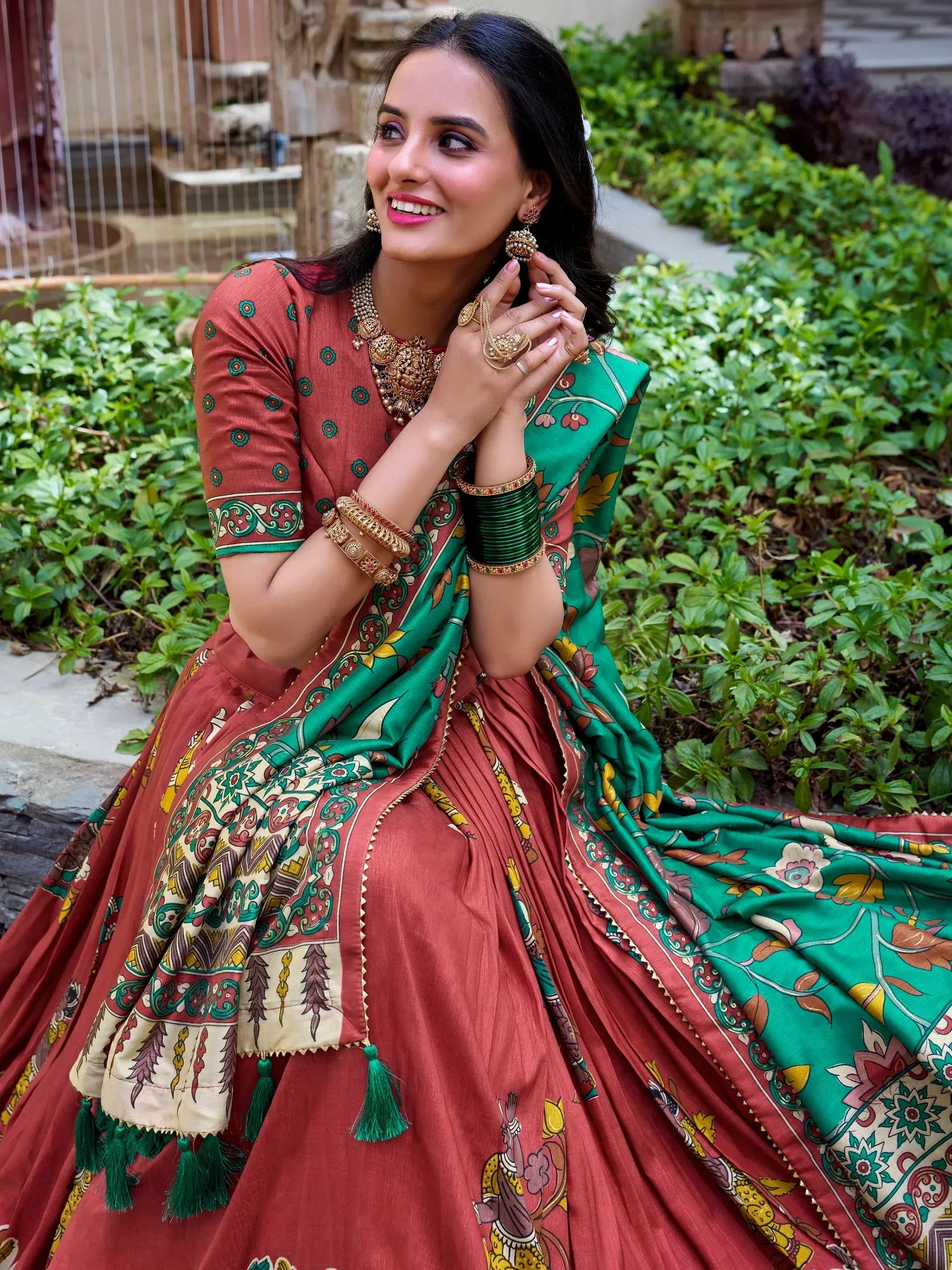 Woman in traditional Indian lehenga choli with green dupatta, floral print, and gold jewelry, perfect for ethnic occasions.