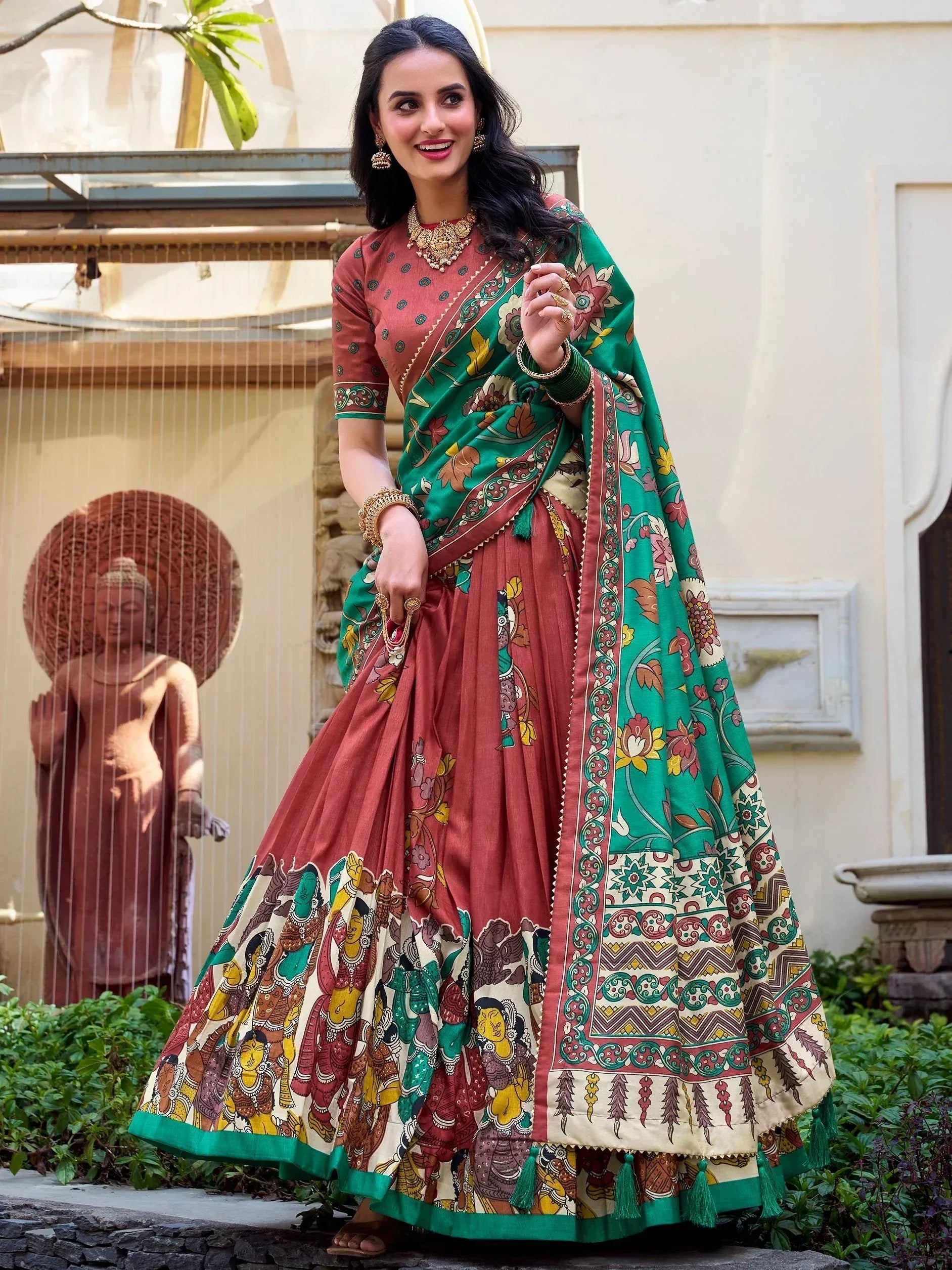 Woman in designer lehenga choli with floral and tribal print, green dupatta, ethnic jewelry