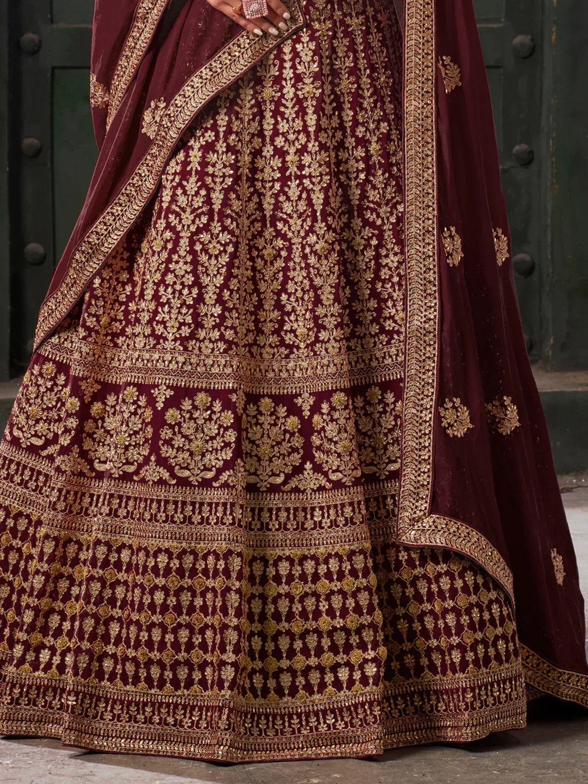 Maroon velvet lehenga with intricate gold embroidery, perfect for Indian weddings and festive occasions.