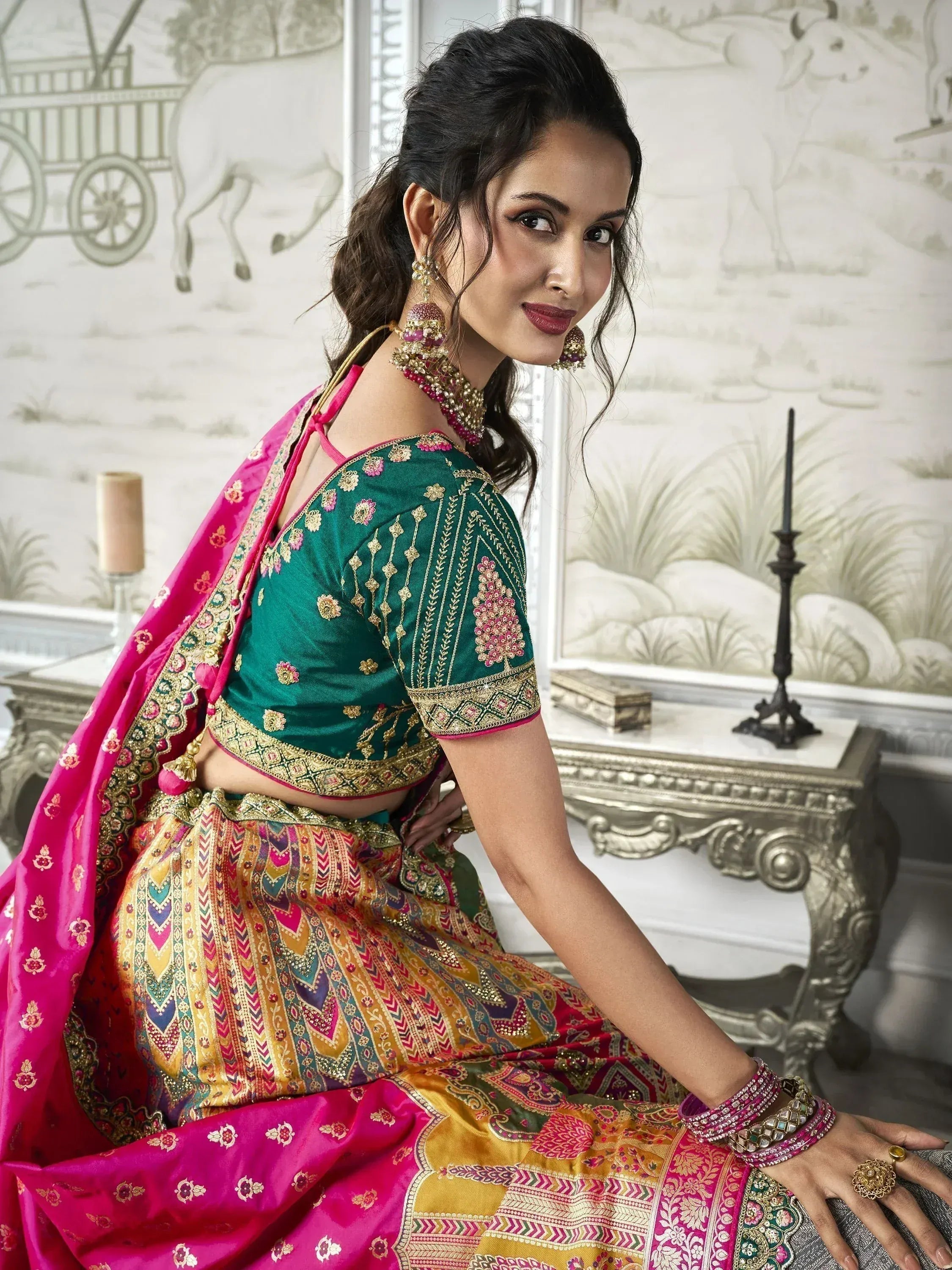 Woman in vibrant green and pink embroidered lehenga choli with gold detailing, perfect for Indian ethnic occasions