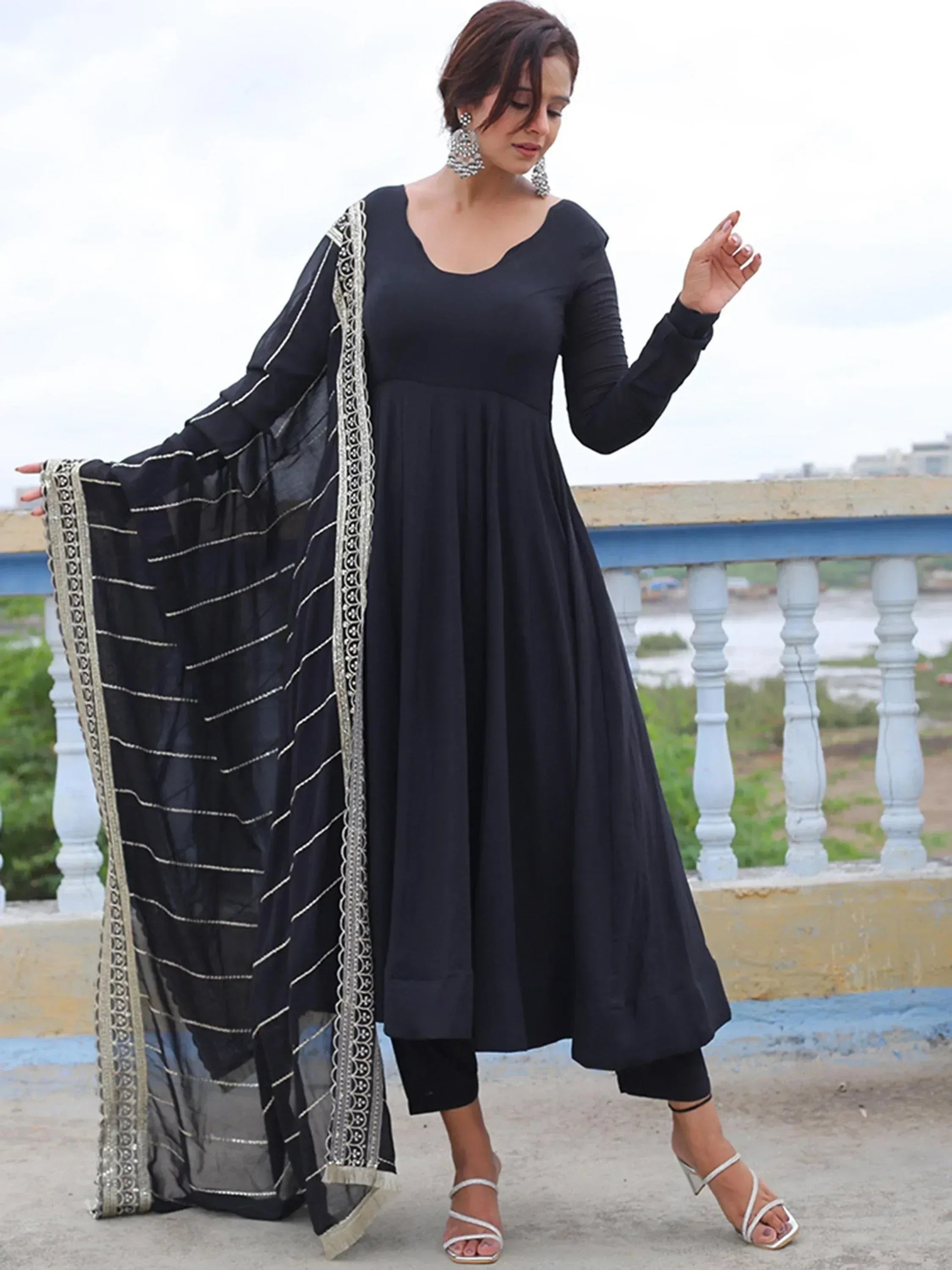 Black ethnic gown with gold embroidery and sheer dupatta, styled with silver heels and statement earrings