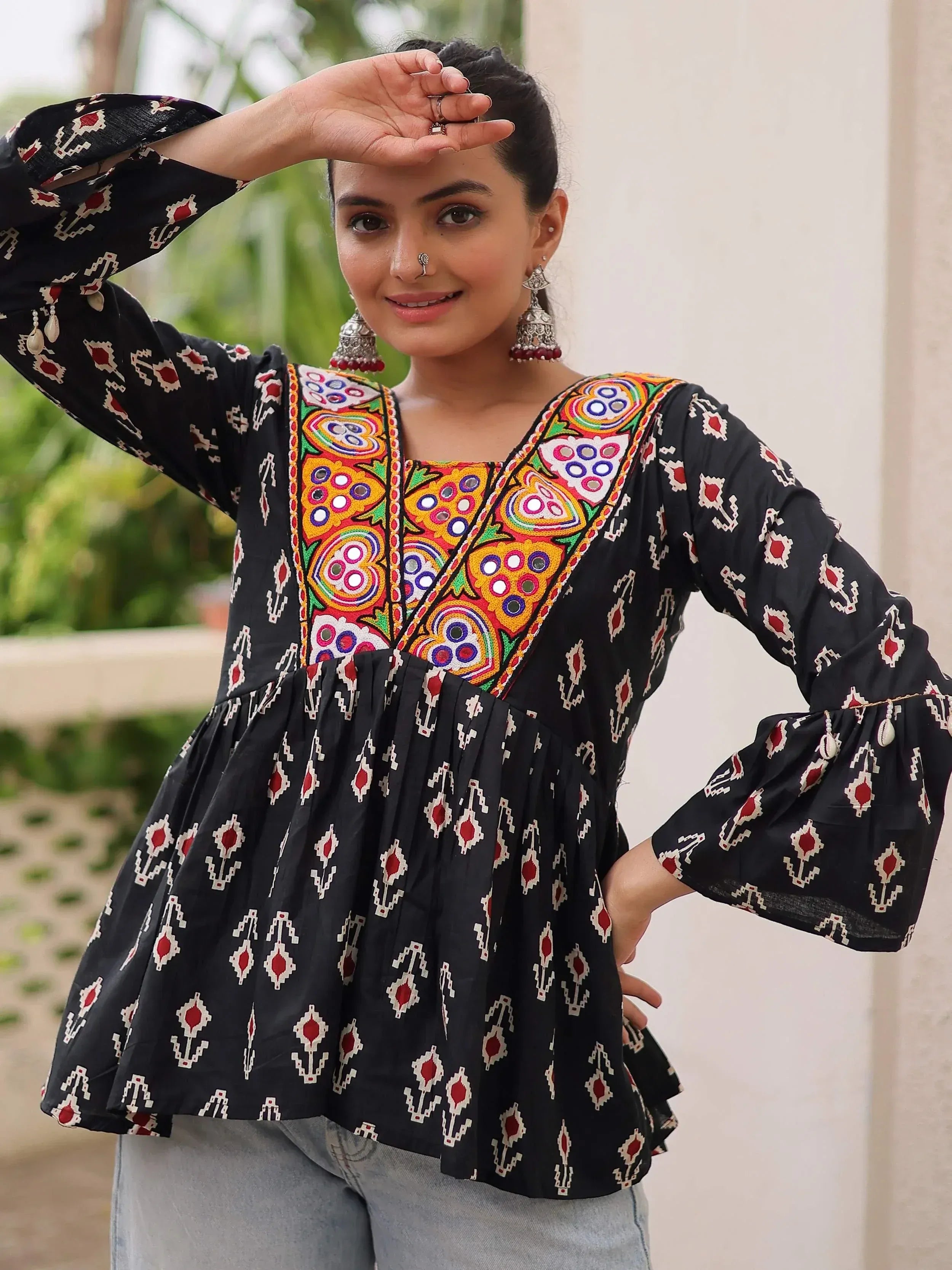 Black ethnic kurti with colorful mirror embroidery and geometric print, paired with jeans for casual wear.