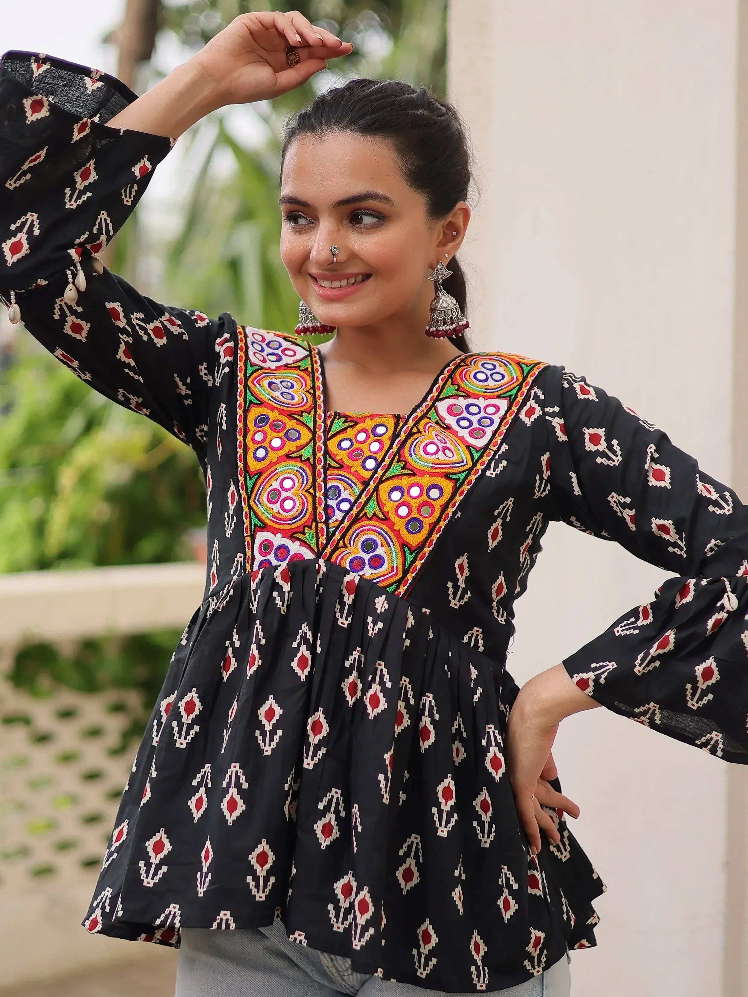 Black ethnic kurti with colorful mirror embroidery and bell sleeves, paired with jeans for casual wear