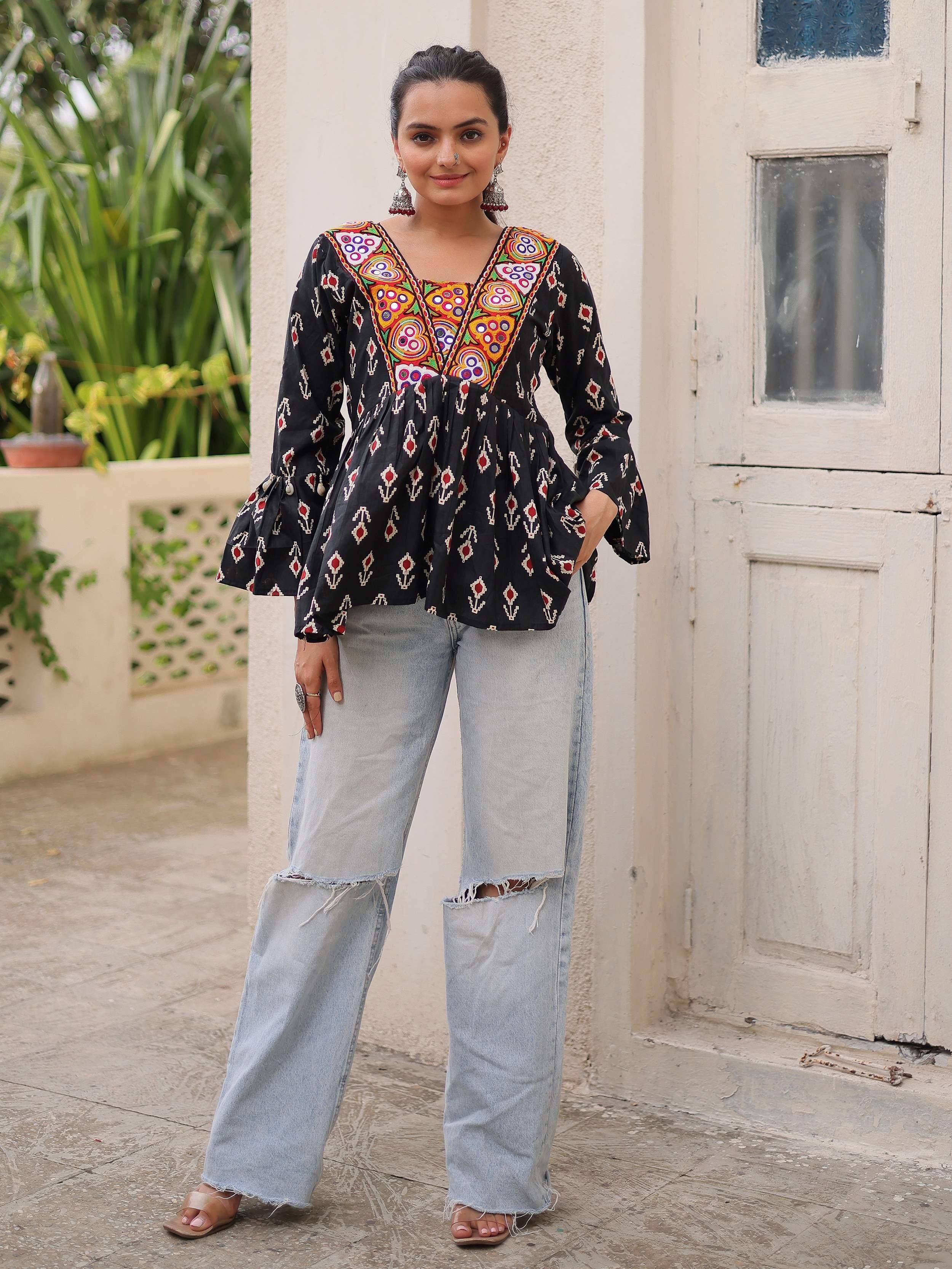 Black embroidered ethnic top with bell sleeves paired with ripped wide-leg jeans, styled for casual wear.