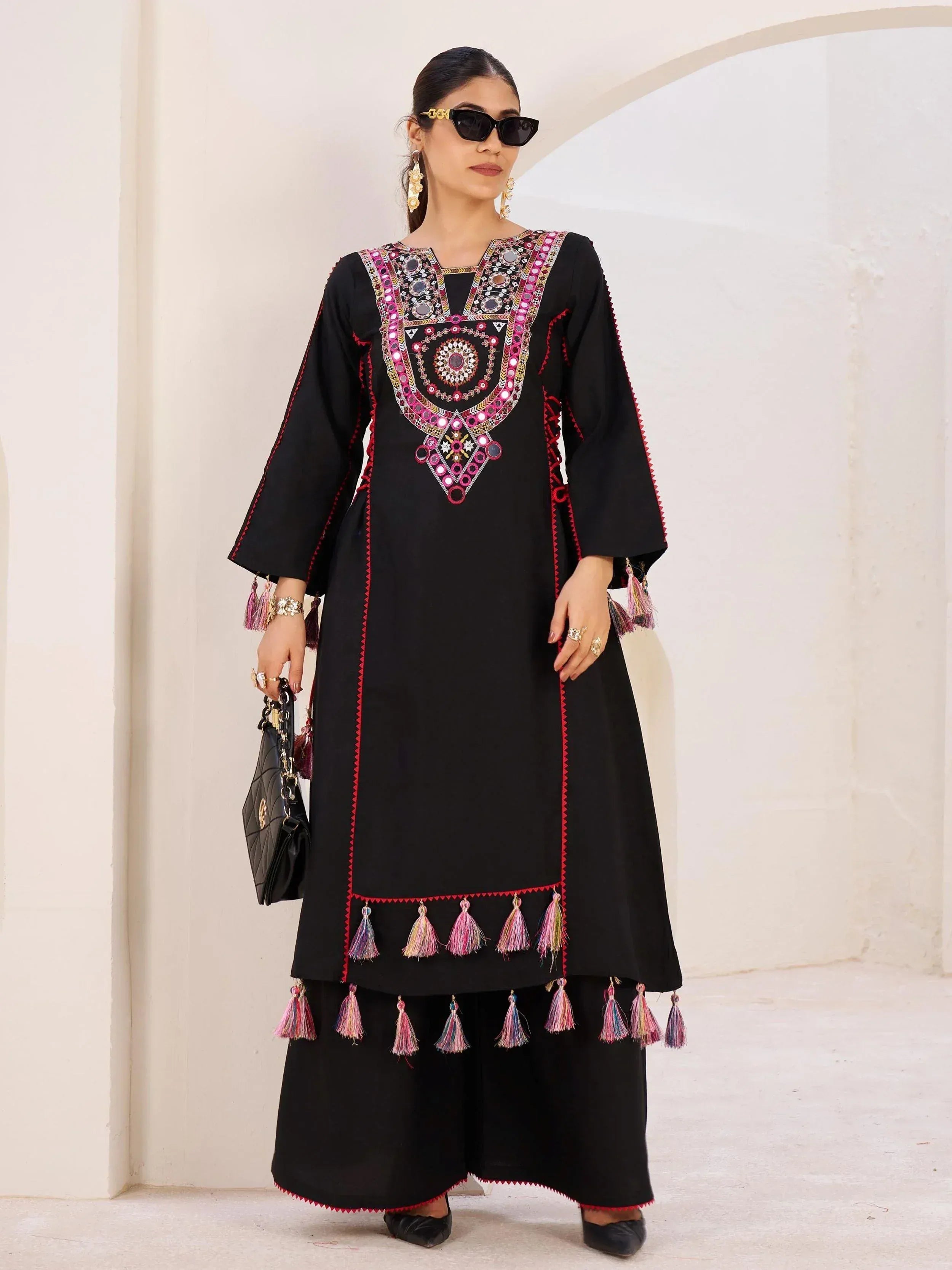 Black ethnic kurti with mirror work and tassels, paired with palazzo pants for festive wear
