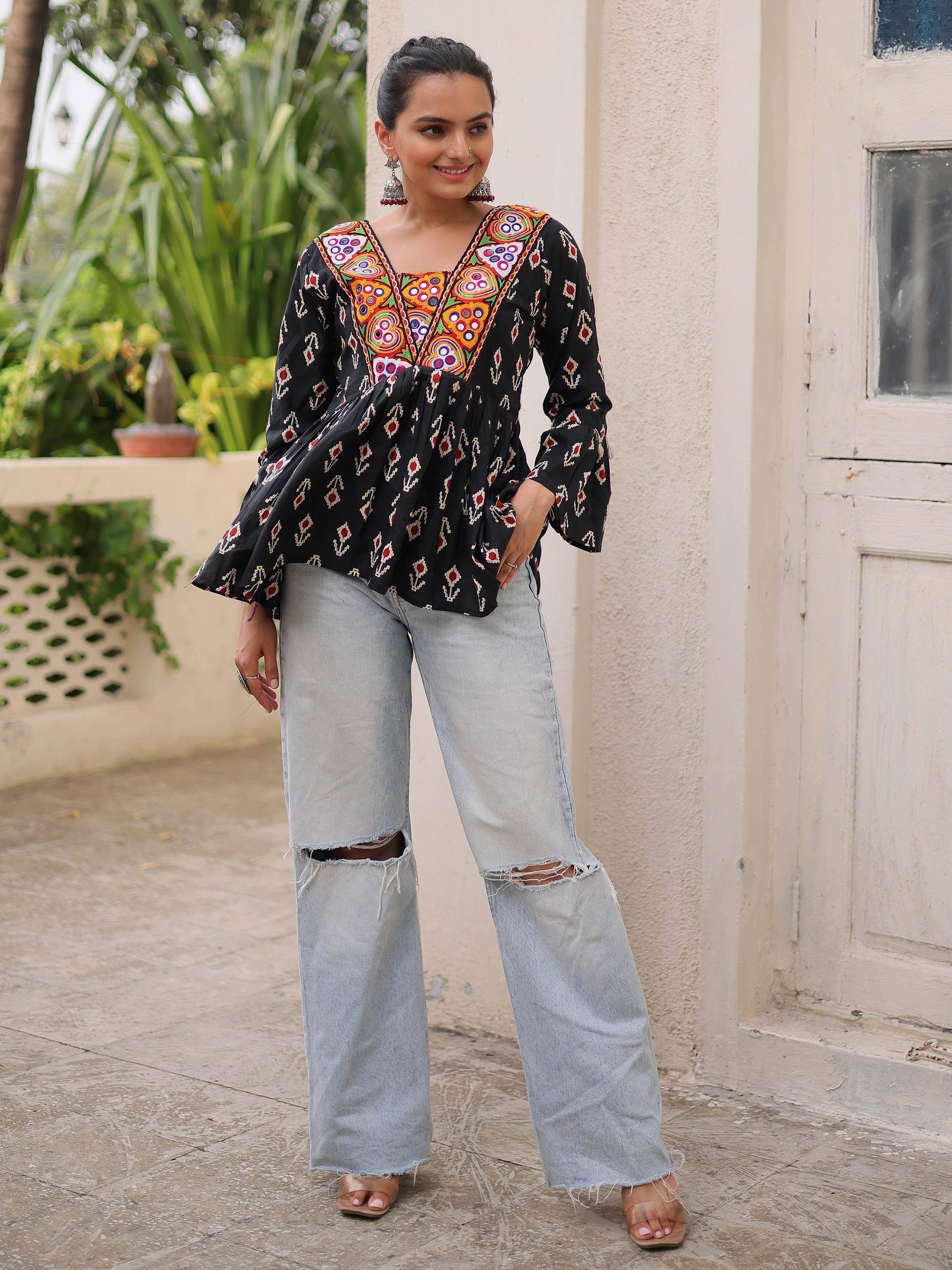 Black embroidered ethnic top with colorful mirror work, paired with ripped wide-leg jeans for a fusion look