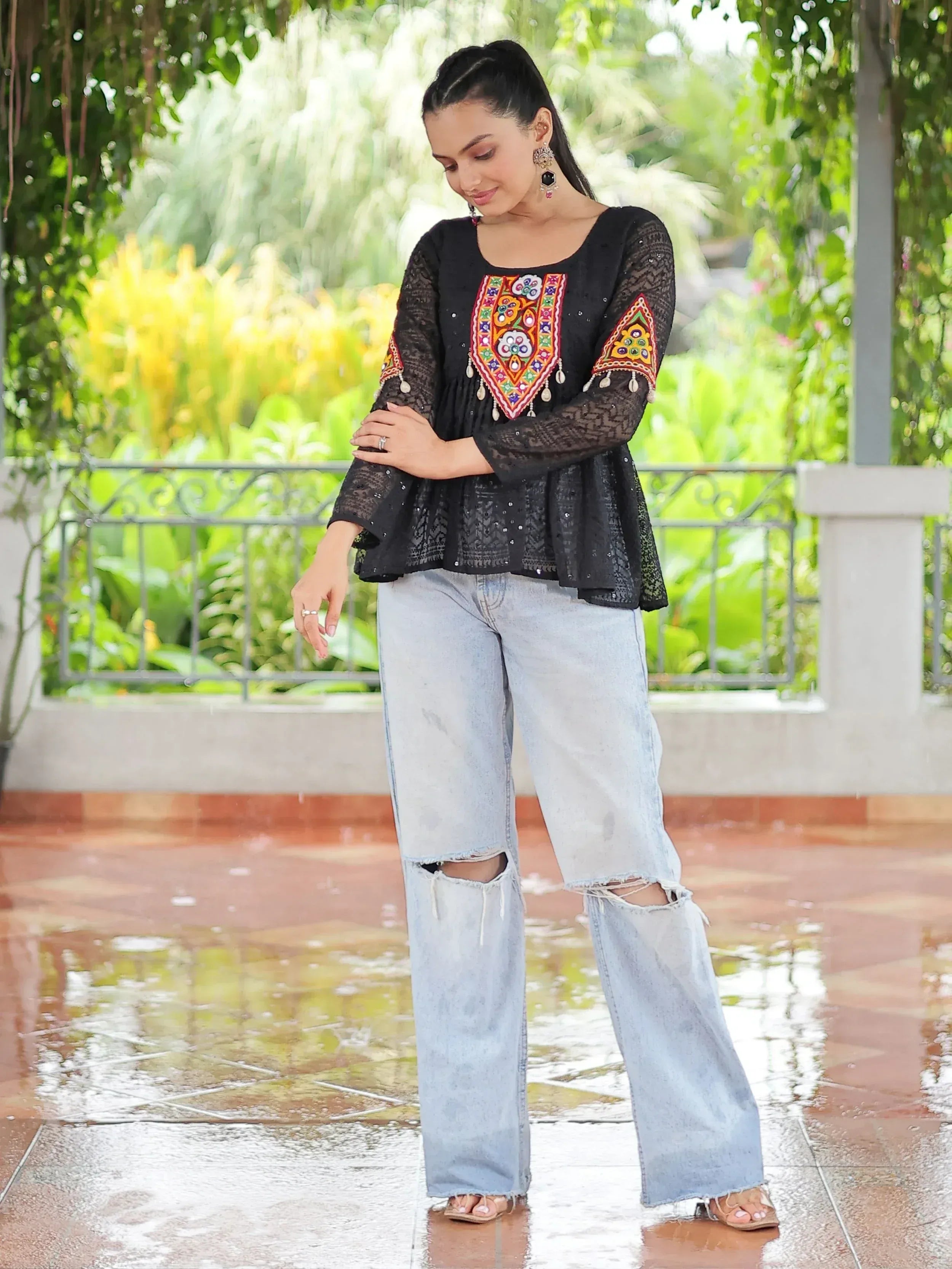 Black embroidered ethnic top with lace sleeves paired with ripped jeans, styled for casual wear.