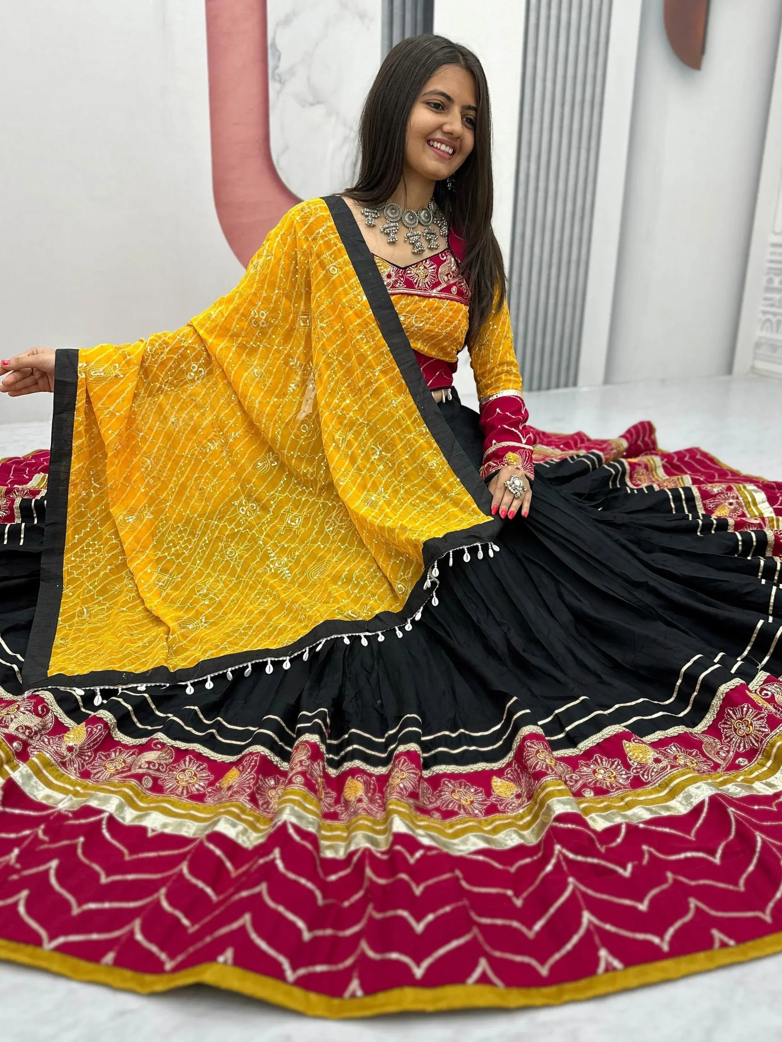 Woman in vibrant yellow and maroon ethnic lehenga choli with black skirt, perfect for Indian festivals and weddings.