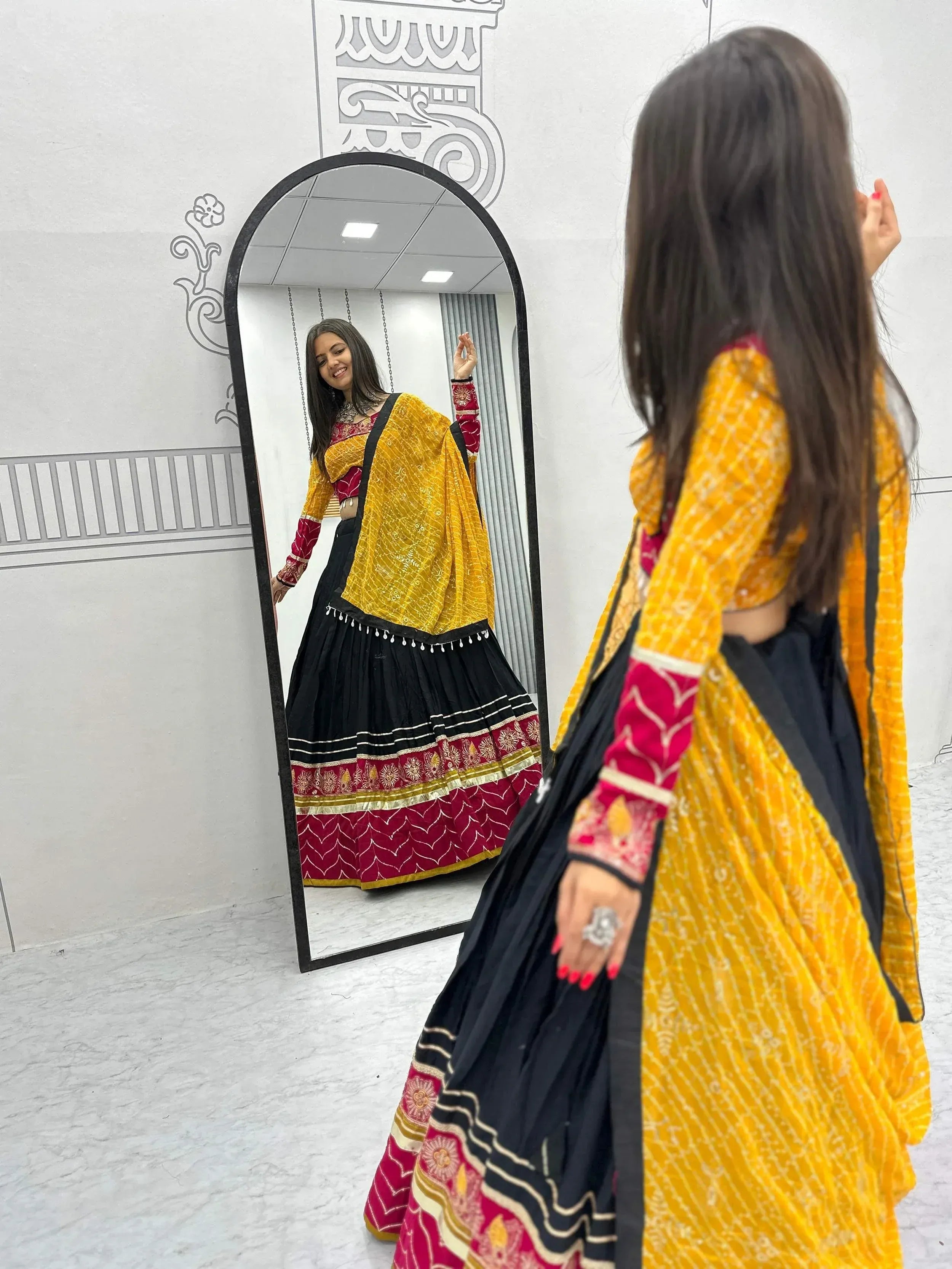 Woman in yellow and black ethnic lehenga choli with mirror reflection, traditional Indian wear