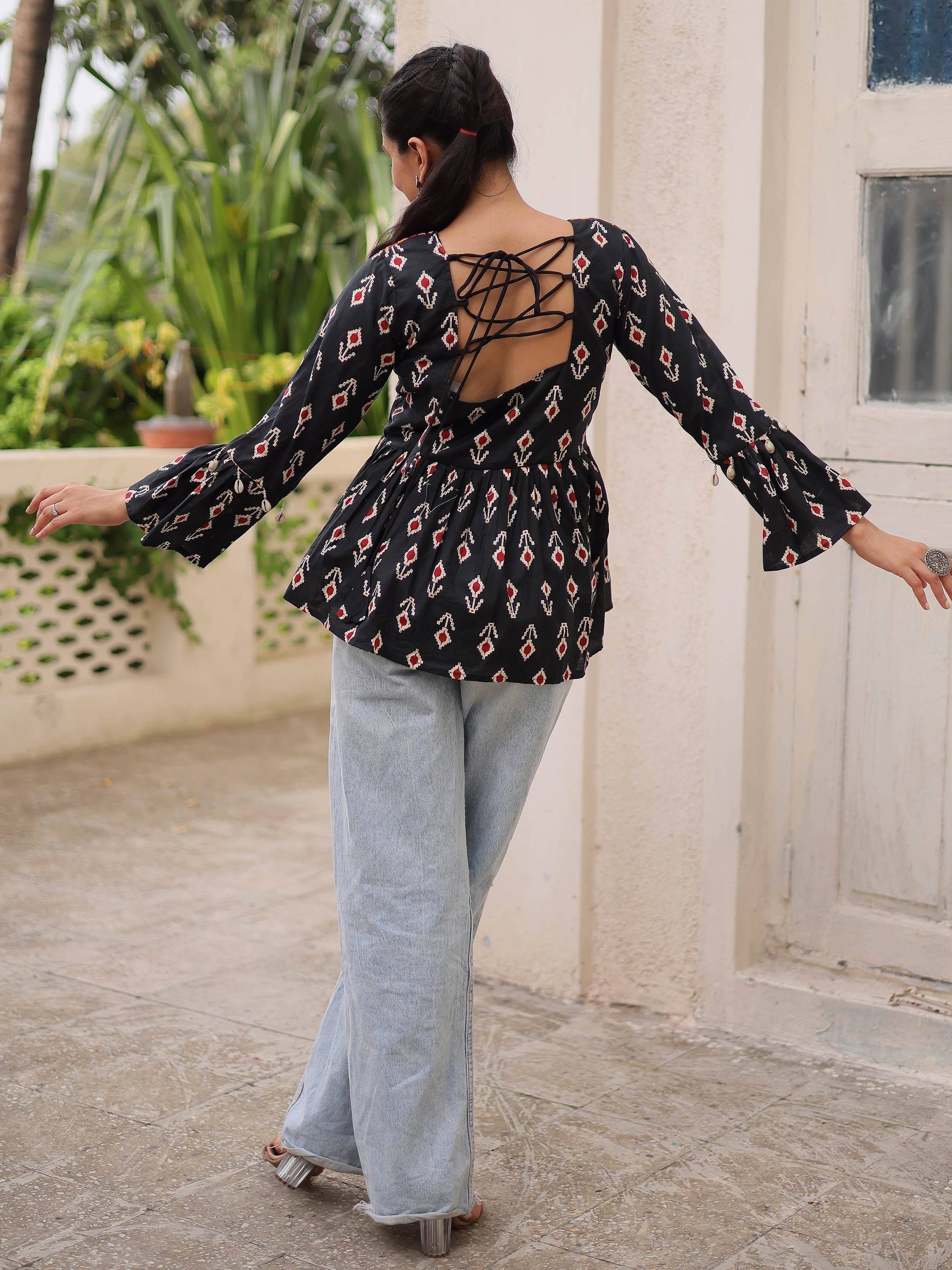 Black printed ethnic top with lace-up back and flared sleeves, paired with wide-leg jeans