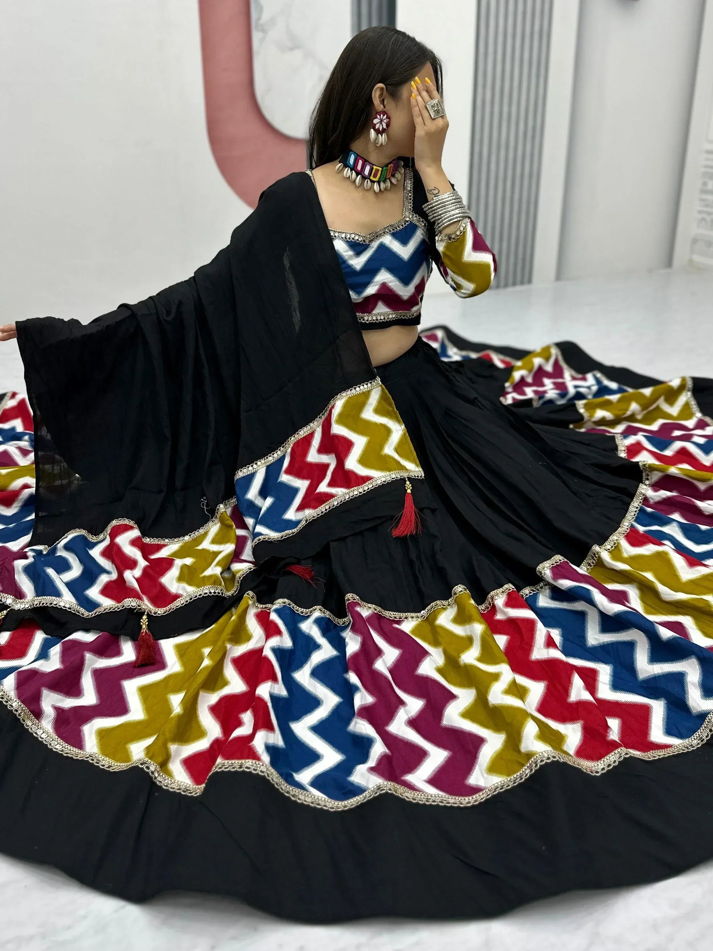 Woman in black lehenga with colorful zigzag print, ethnic choli, and dupatta, perfect for Indian festive wear.