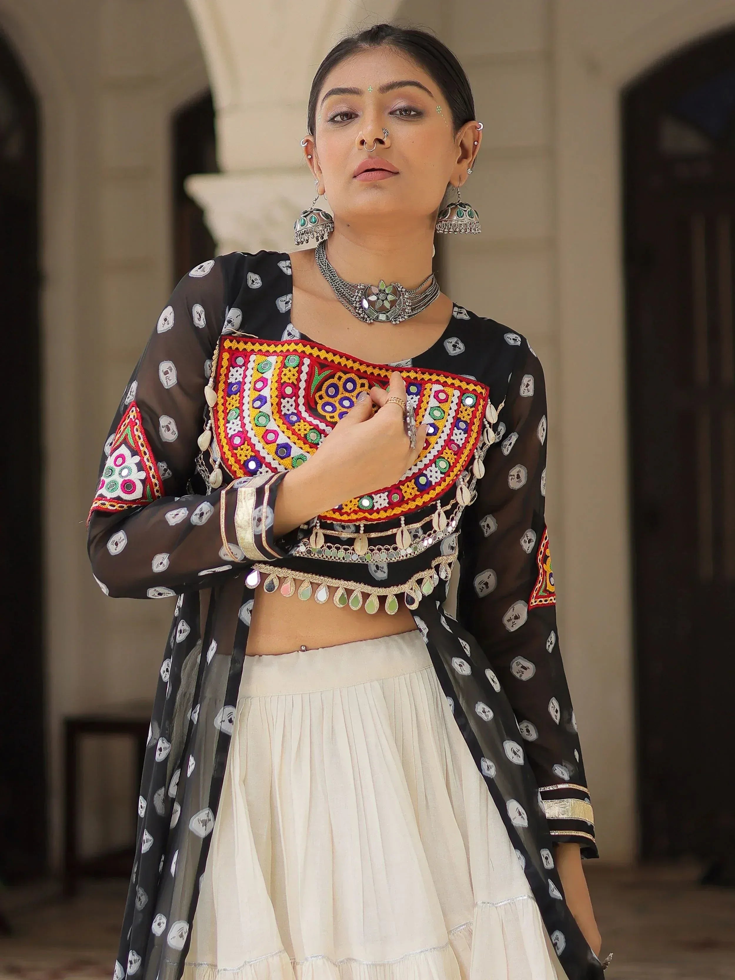 Black and white ethnic lehenga choli with colorful mirror work and skull print, paired with traditional jewelry